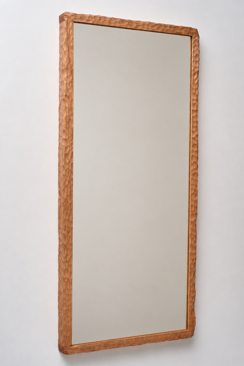 Full-length mirror with a wooden textured frame hanging on a white wall.