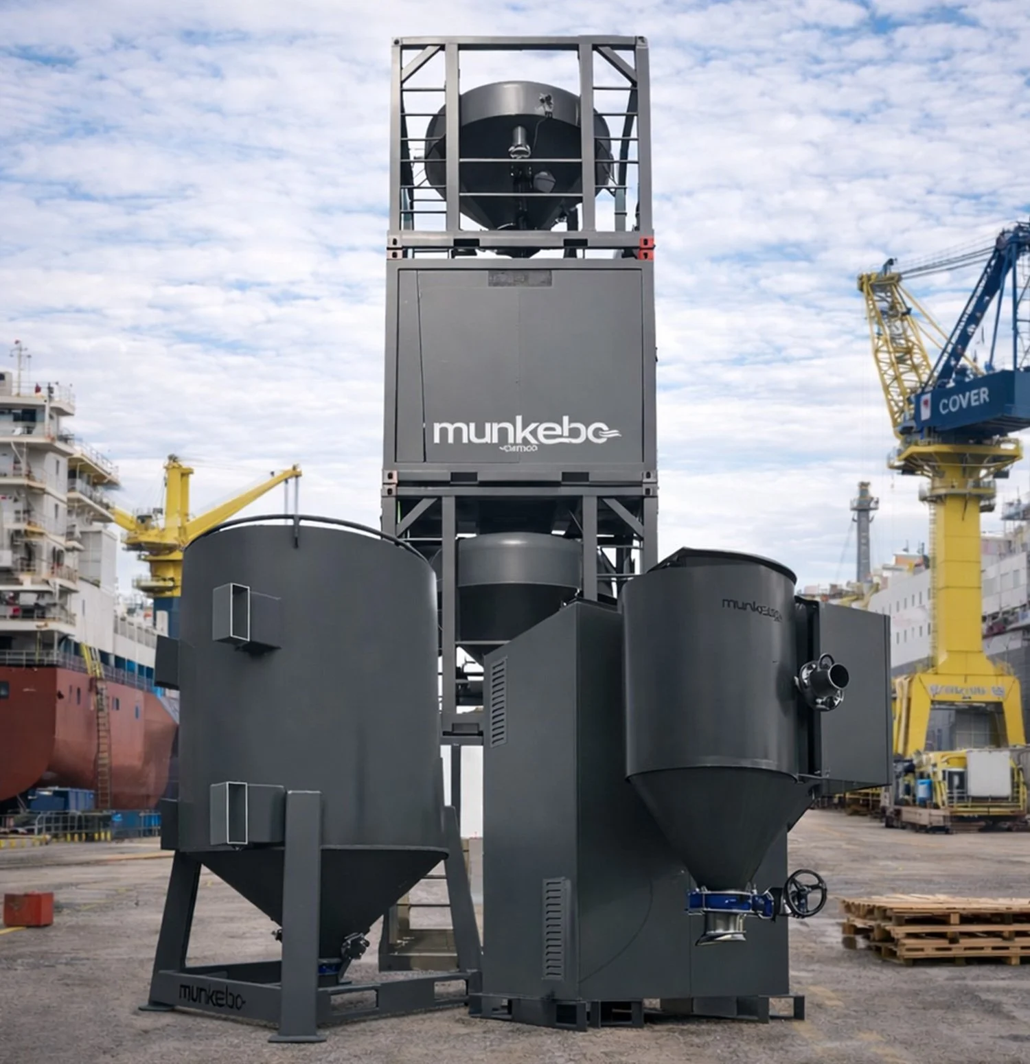 Industrial equipment with large metal tanks and machinery, labeled 'munkebø,' situated in a shipyard with ships and cranes in the background under a cloudy sky.
