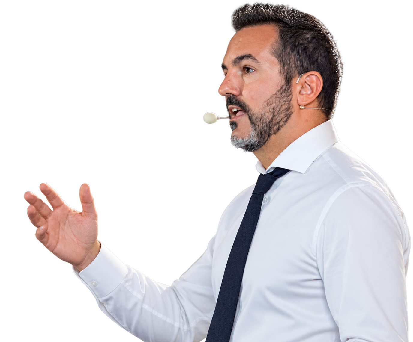 Man wearing a white shirt and black tie speaking into a headset microphone, gesturing with his hand.