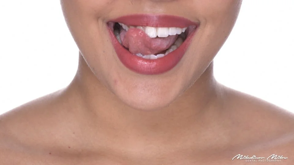 A woman with pink lipstick sticking out her tongue, showing her teeth and tongue.