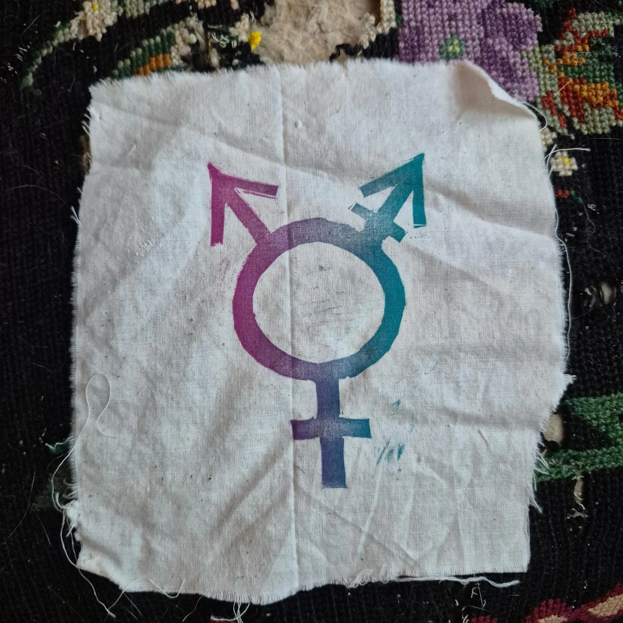 A pink and white graphic of a block print illustrating a ceramic pitcher with flames and a pansy flower, with the word 'R.A.C.K.' at the bottom.