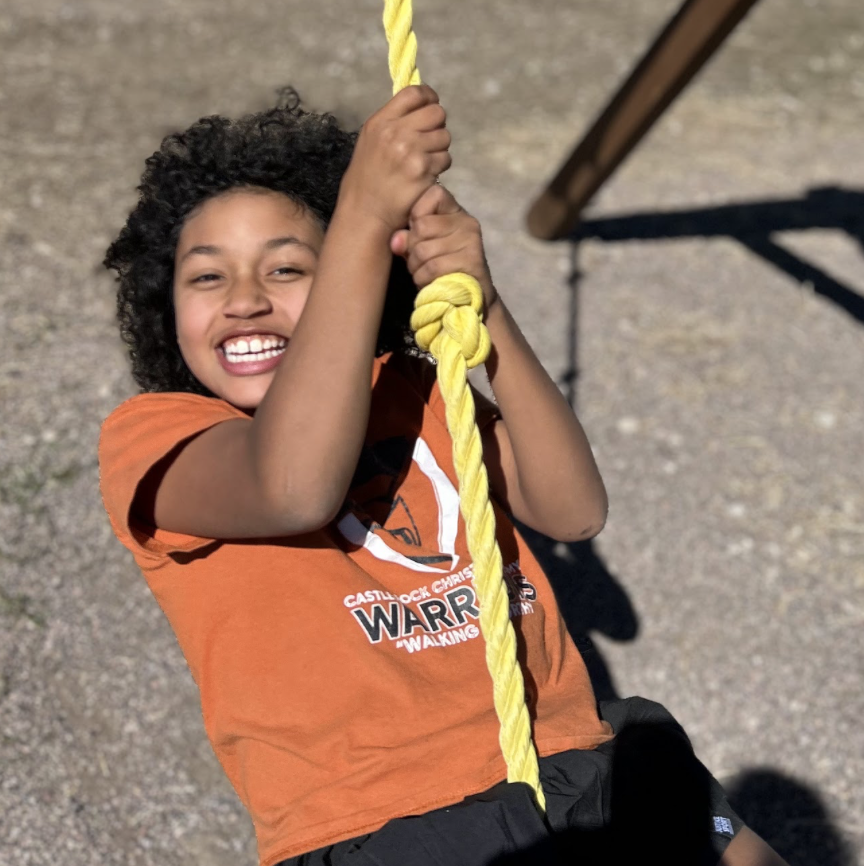 4th grade student smiling on rope swing