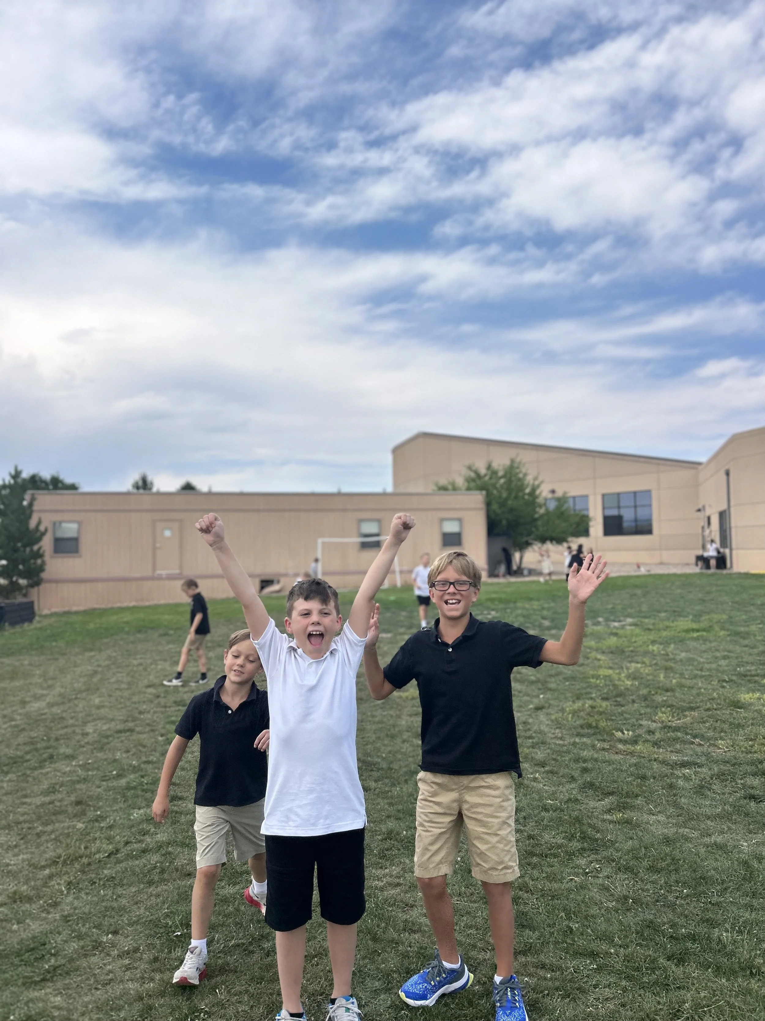 Students smiling and hands up at recess