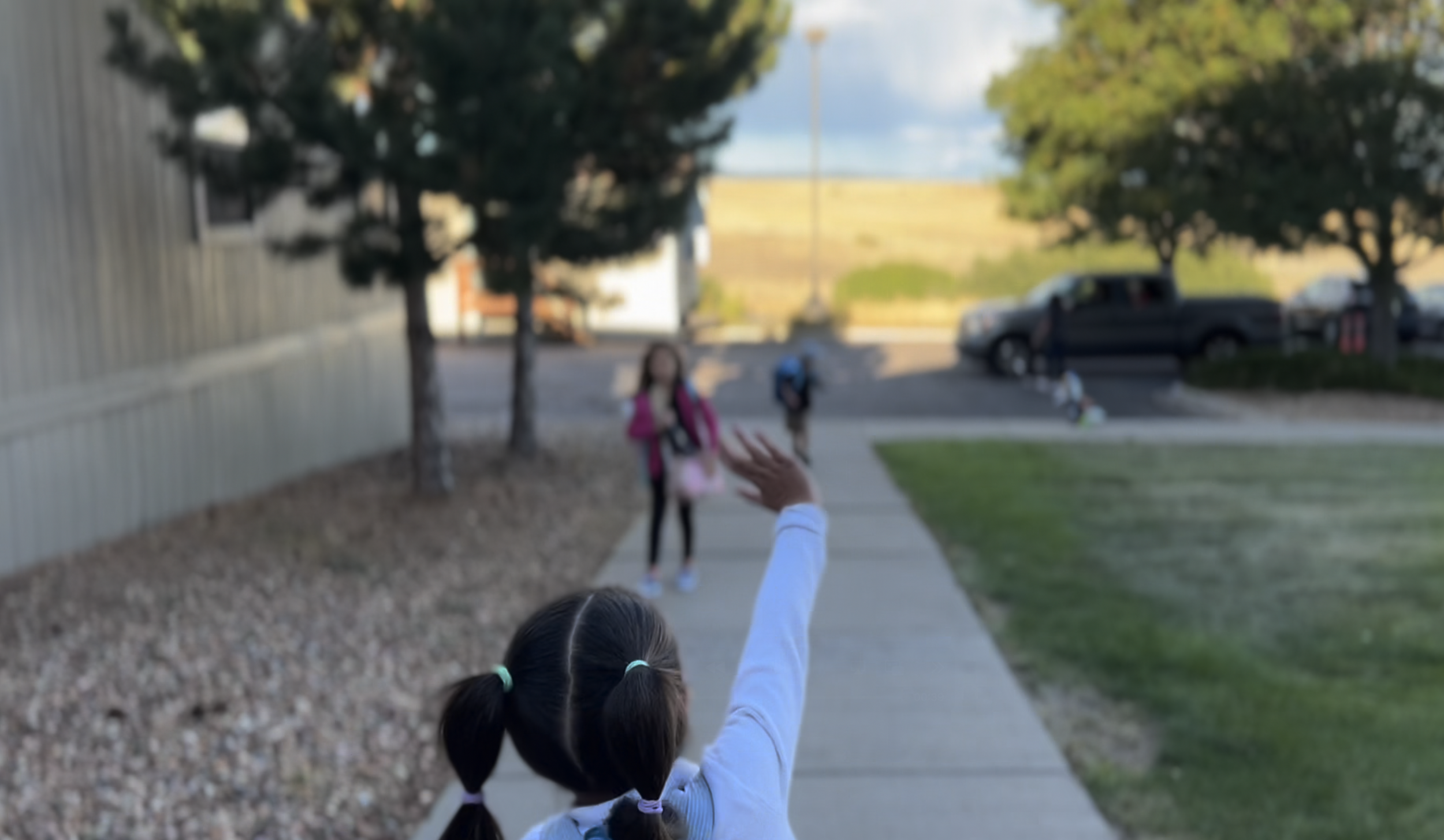 Students welcome each other at carline with waves and smiles