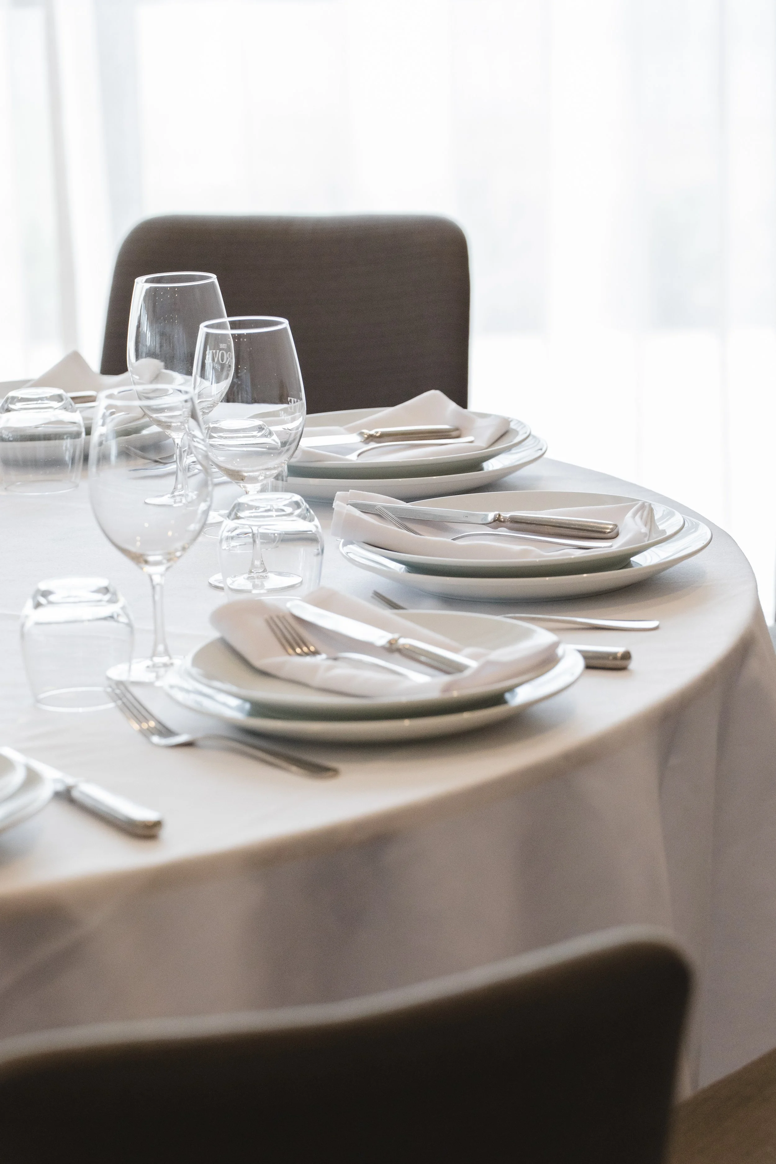 Elegant dining table set with white plates, silverware, napkins, and glasses, set for a meal.