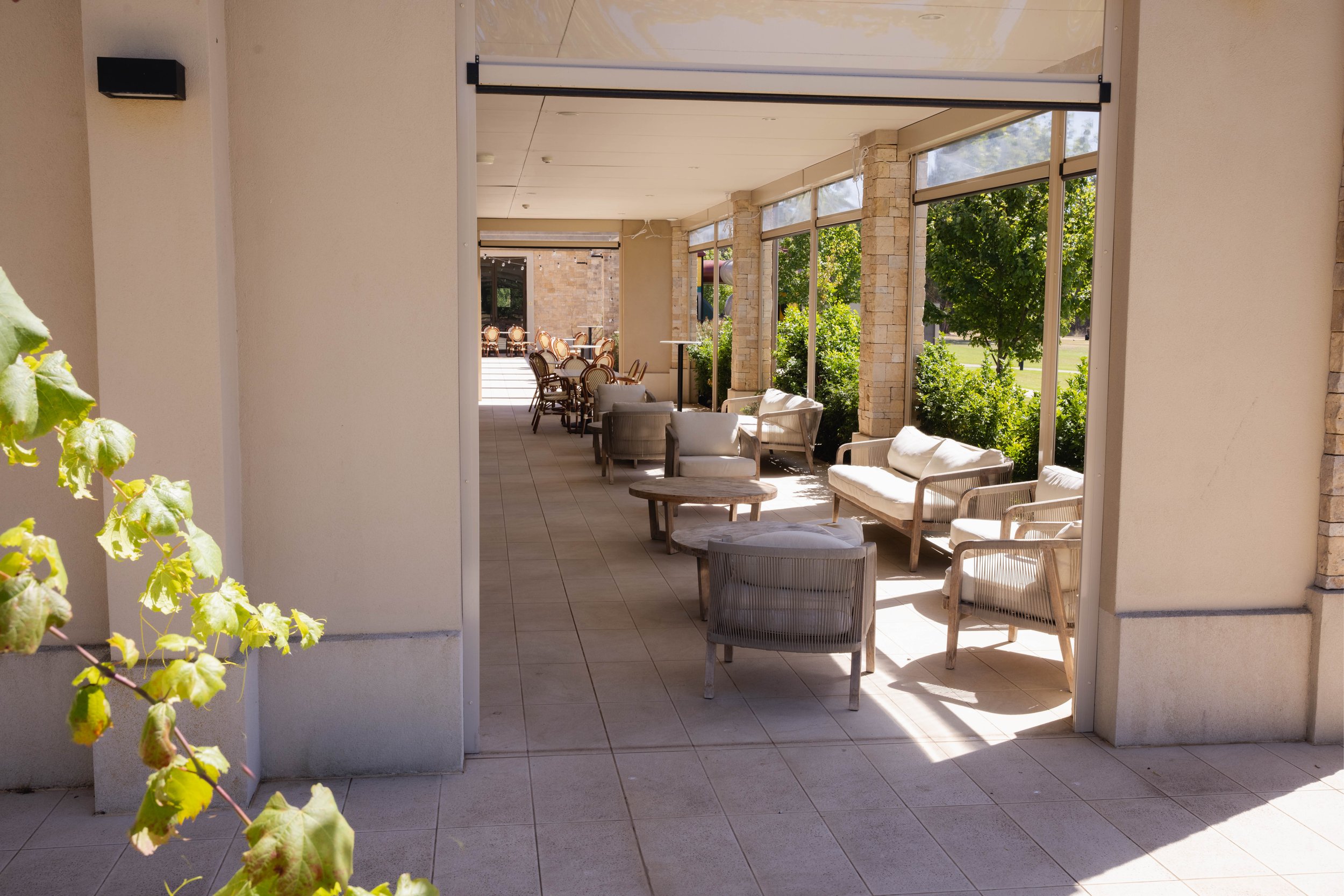 Outdoor patio with wicker chairs, a sofa, potted plants, and high-top tables.