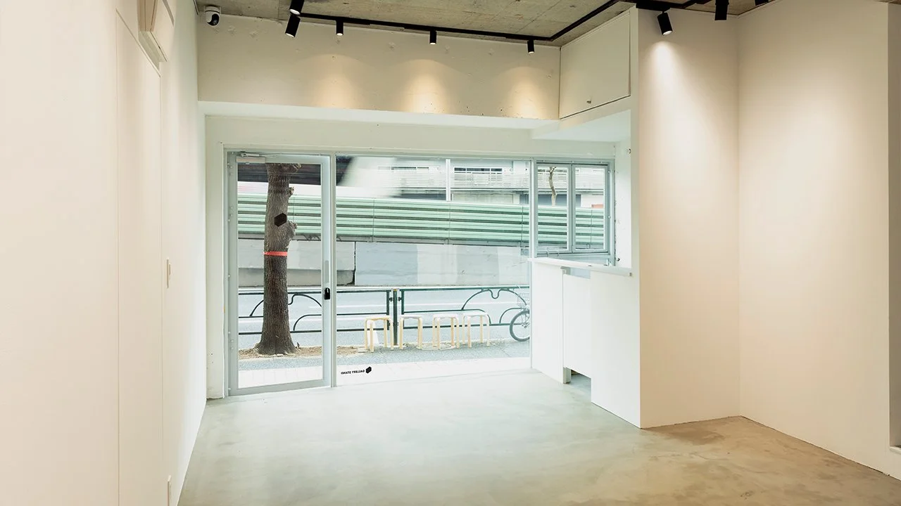 白い壁の室内から外の通りを見ている風景。大きな窓とガラスドア