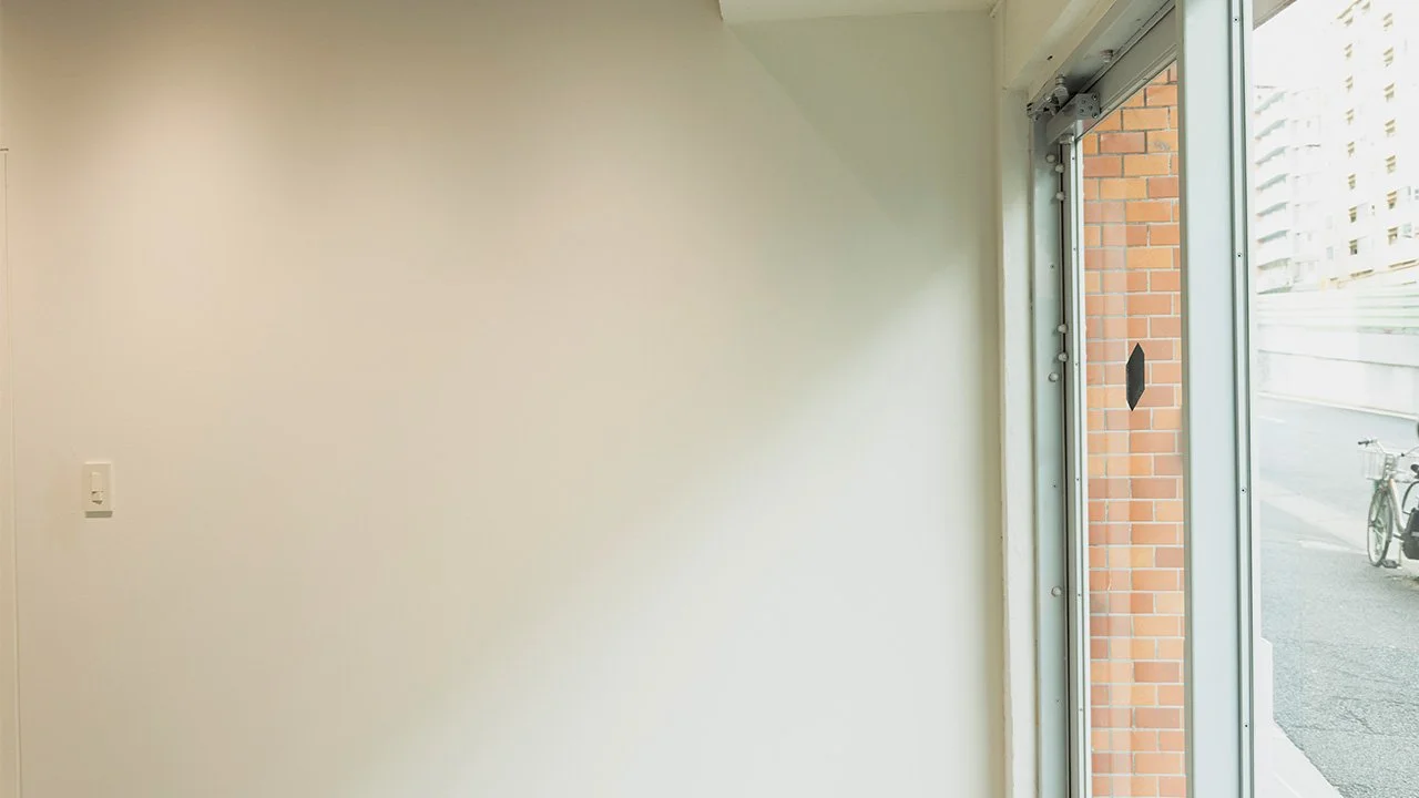 白い壁と横開きのガラスドア、外には自転車と道路が見える