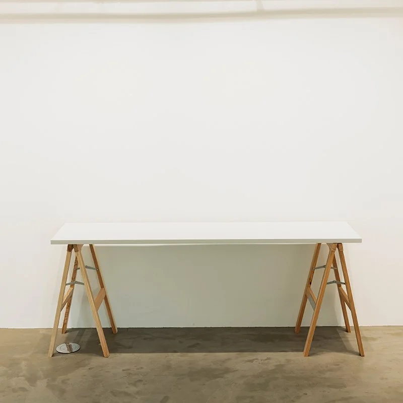 白い壁と白いテーブル、木製の脚がついた簡素なデザインの机
