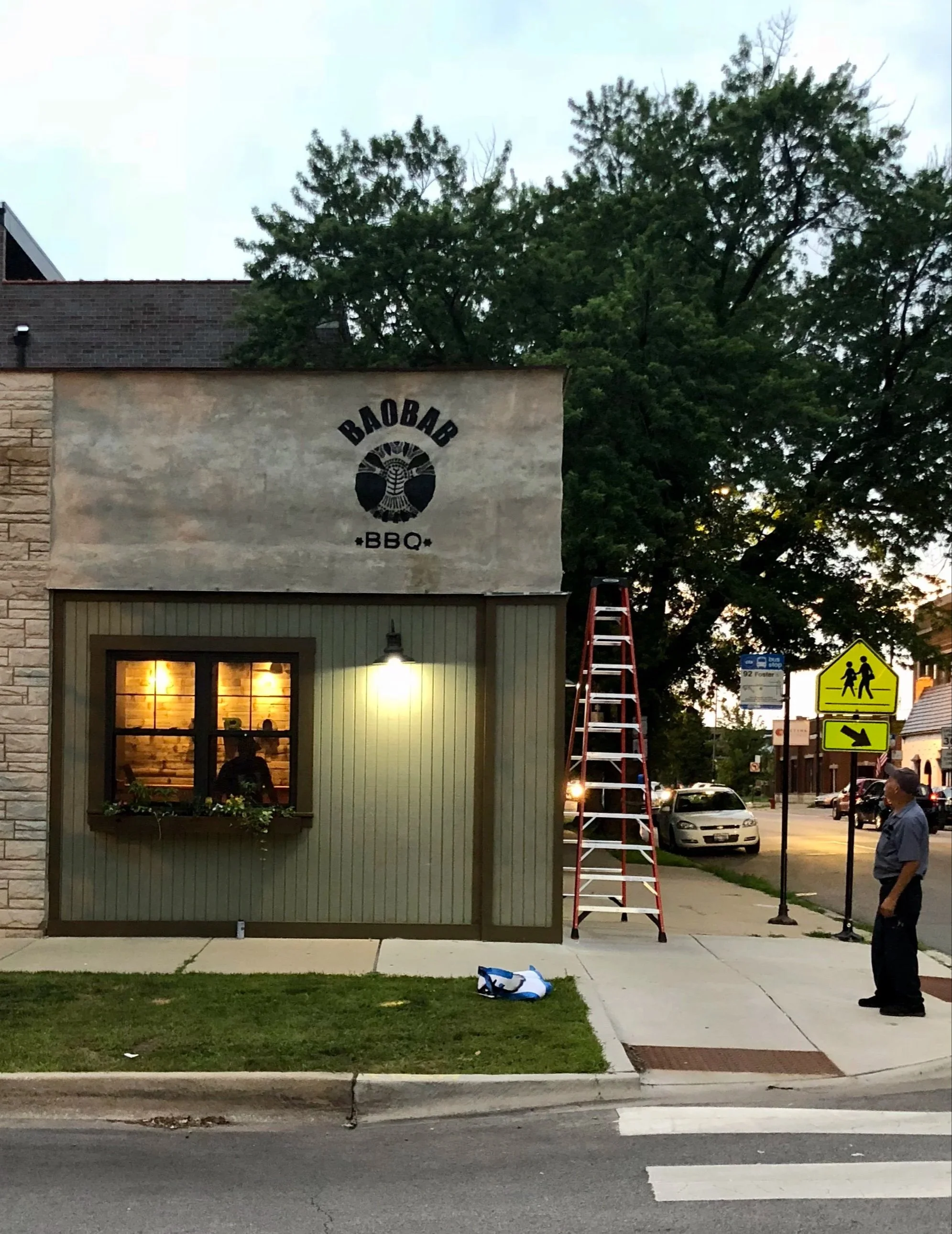 Hand-painted storefront logo for Baobab BBQ using a custom stencil and Montana spray paint on a textured exterior wall, designed to naturally weather over time for a rustic aesthetic.