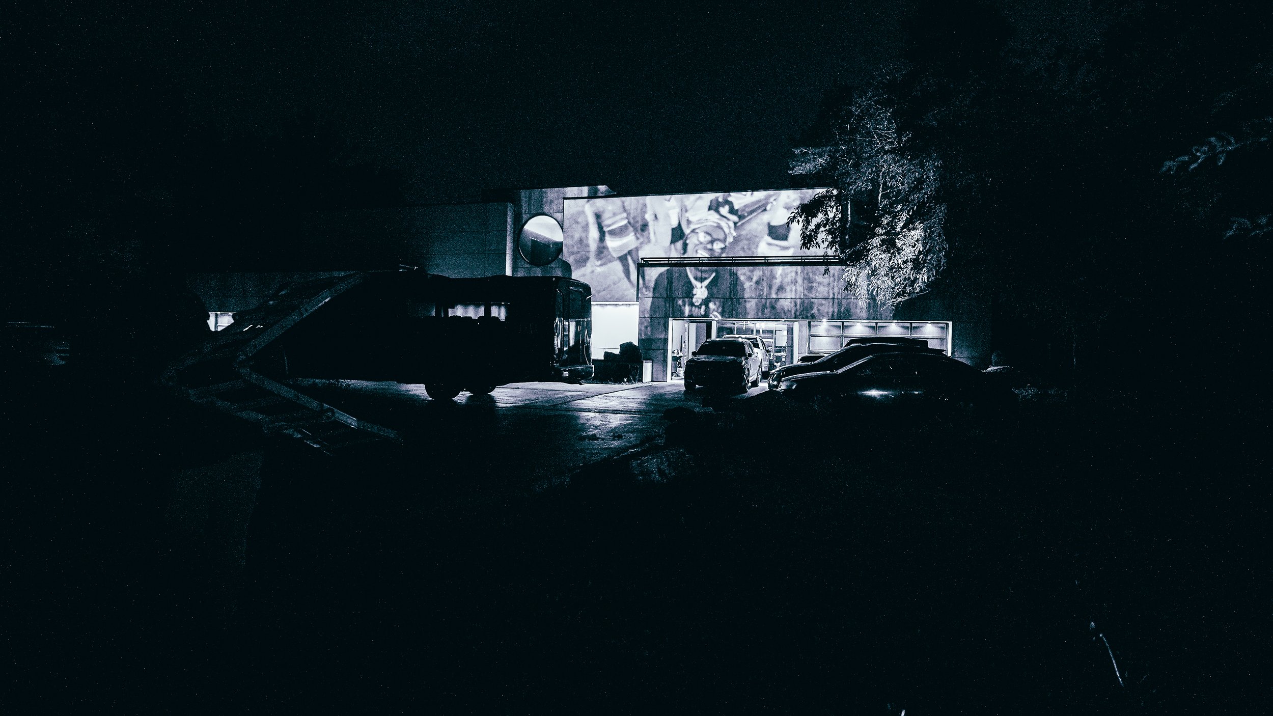 Nighttime view of Dojo Mansion during a private creative gathering featuring outdoor projection mapping, artist networking, and immersive visual experiences documented by DiverCity Artistry.