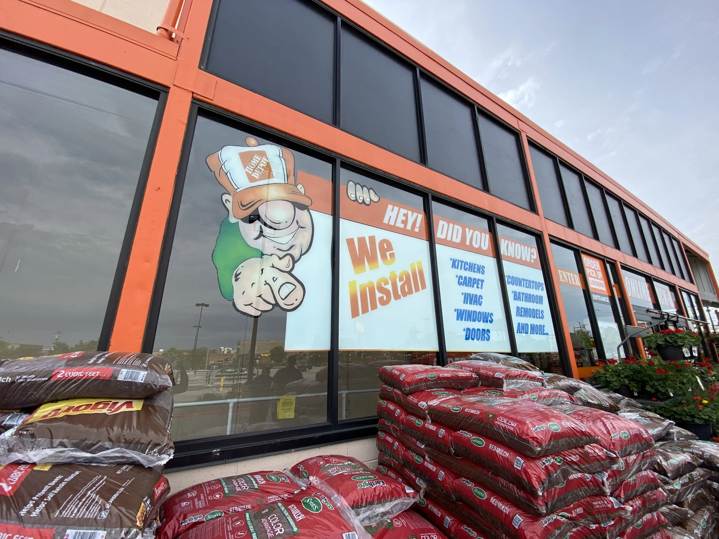 Hand-painted entrance window mural at North Ave Home Depot featuring the Homer mascot and installation service messaging, completed overnight with Montana spray paints and gloss protection.