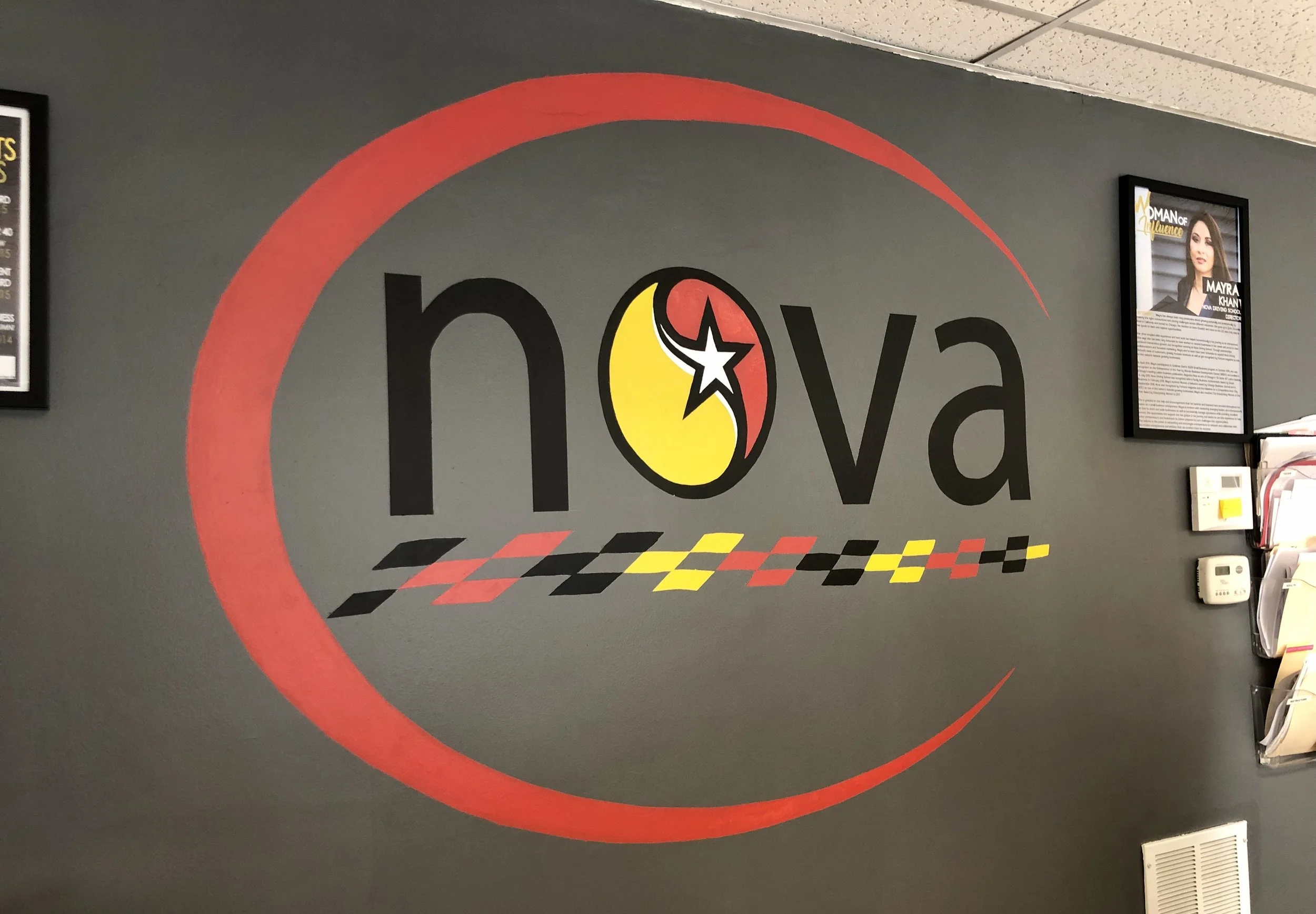 Hand-painted NOVA Driving School logo mural with accurate brand color matching and durable paint materials, designed to reinforce identity in the reception area.