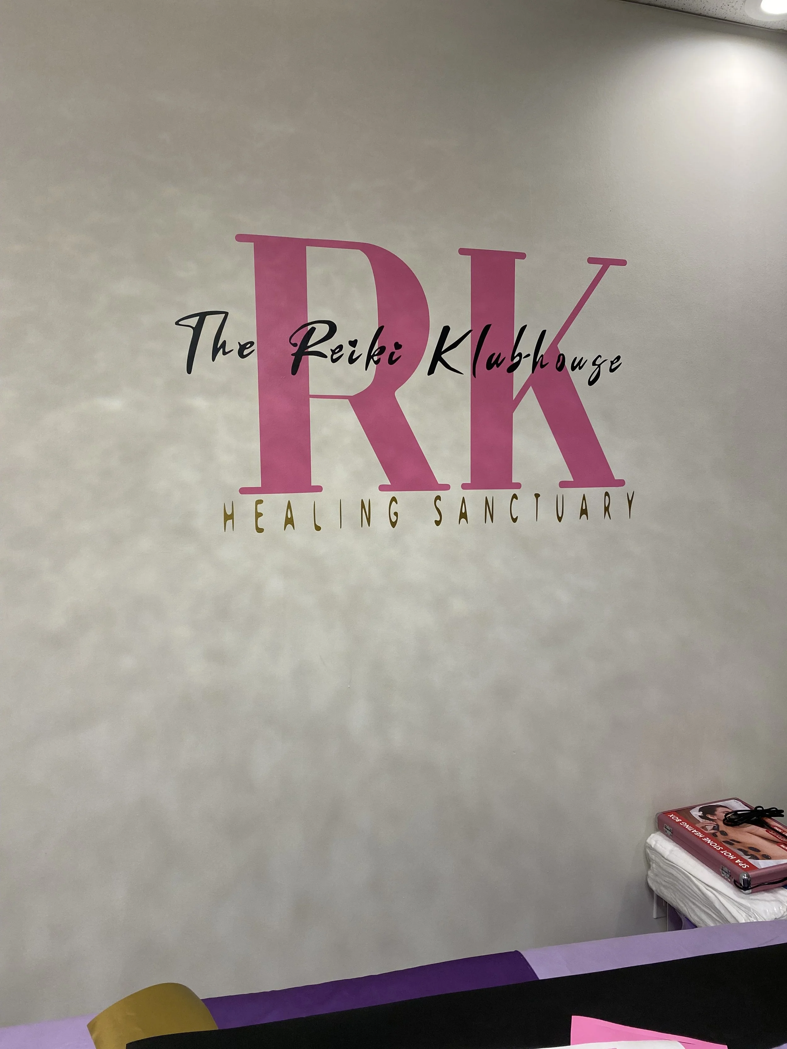 Wall vinyl for The Reiki Klubhouse Healing Sanctuary by Majohani Love Jones, featuring pink, black, and gold layered lettering.
