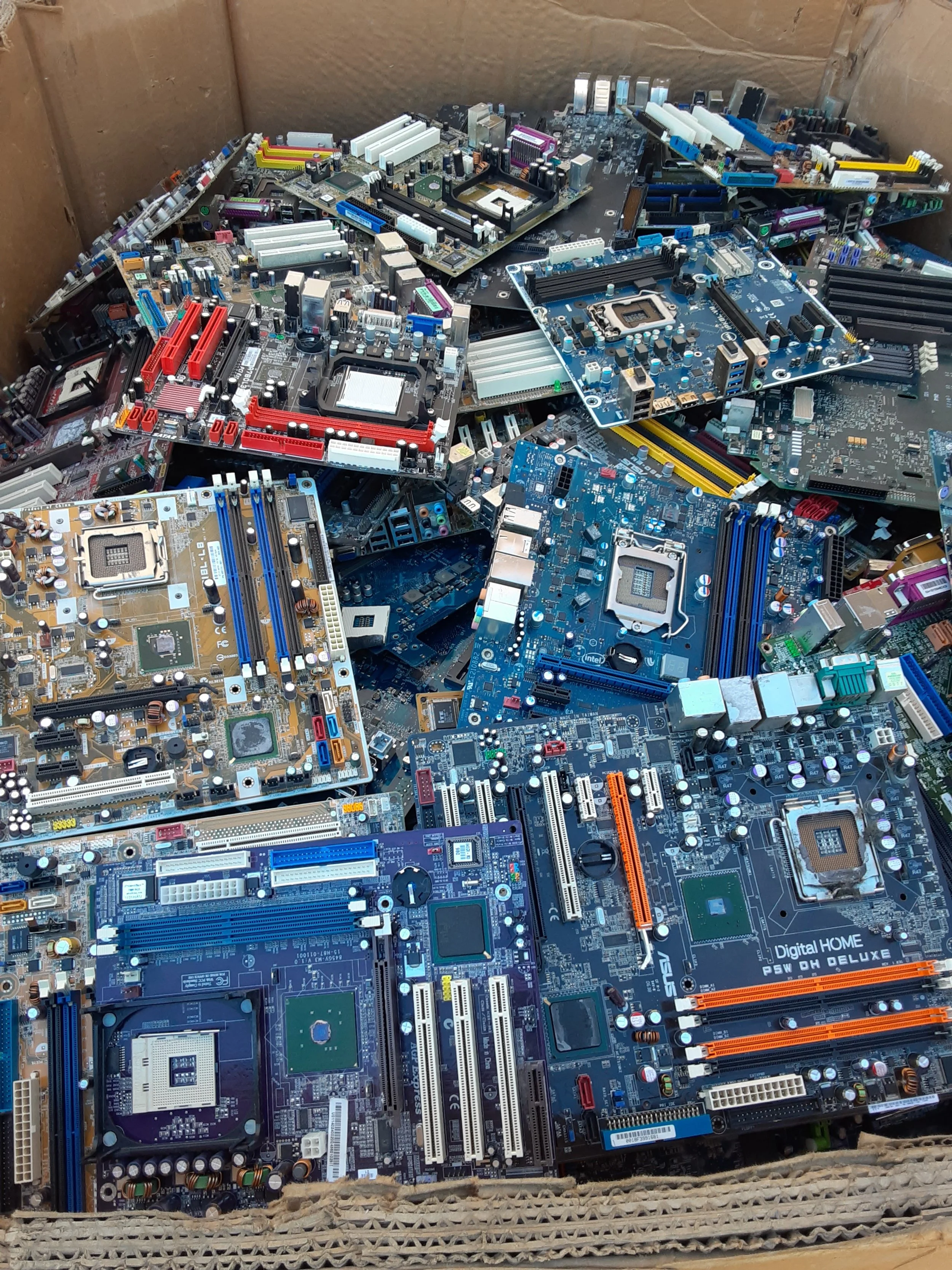 A photo of a gaylord full of variously colored motherboards