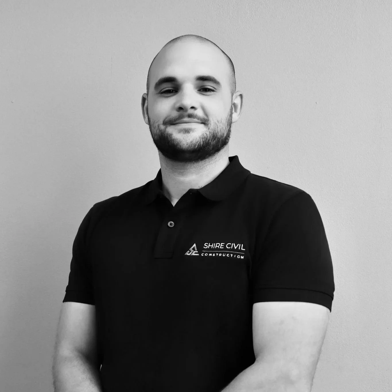 Black and white photo of a man with a serious expression, showing a tattoo on his upper arm, wearing a sleeveless shirt.