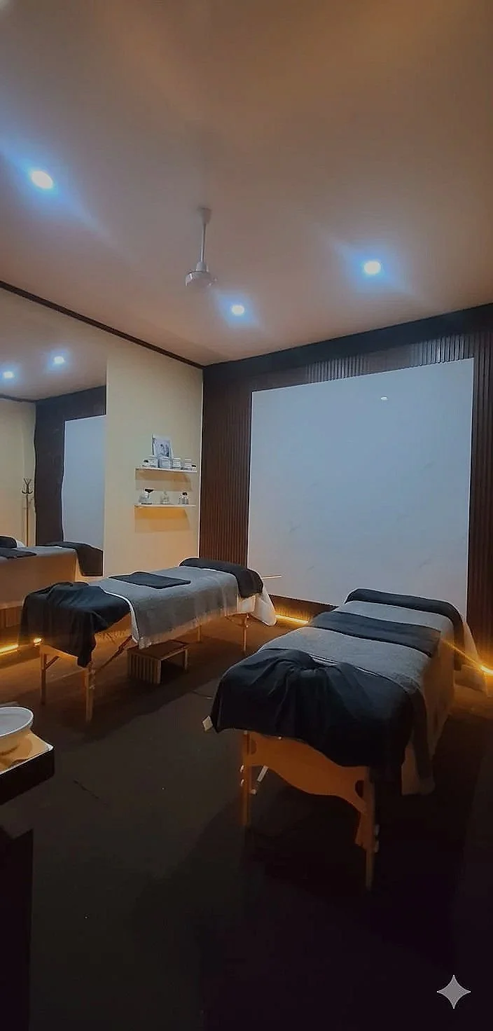 Spa or massage room with three massage beds, dim lighting, and calming decor.