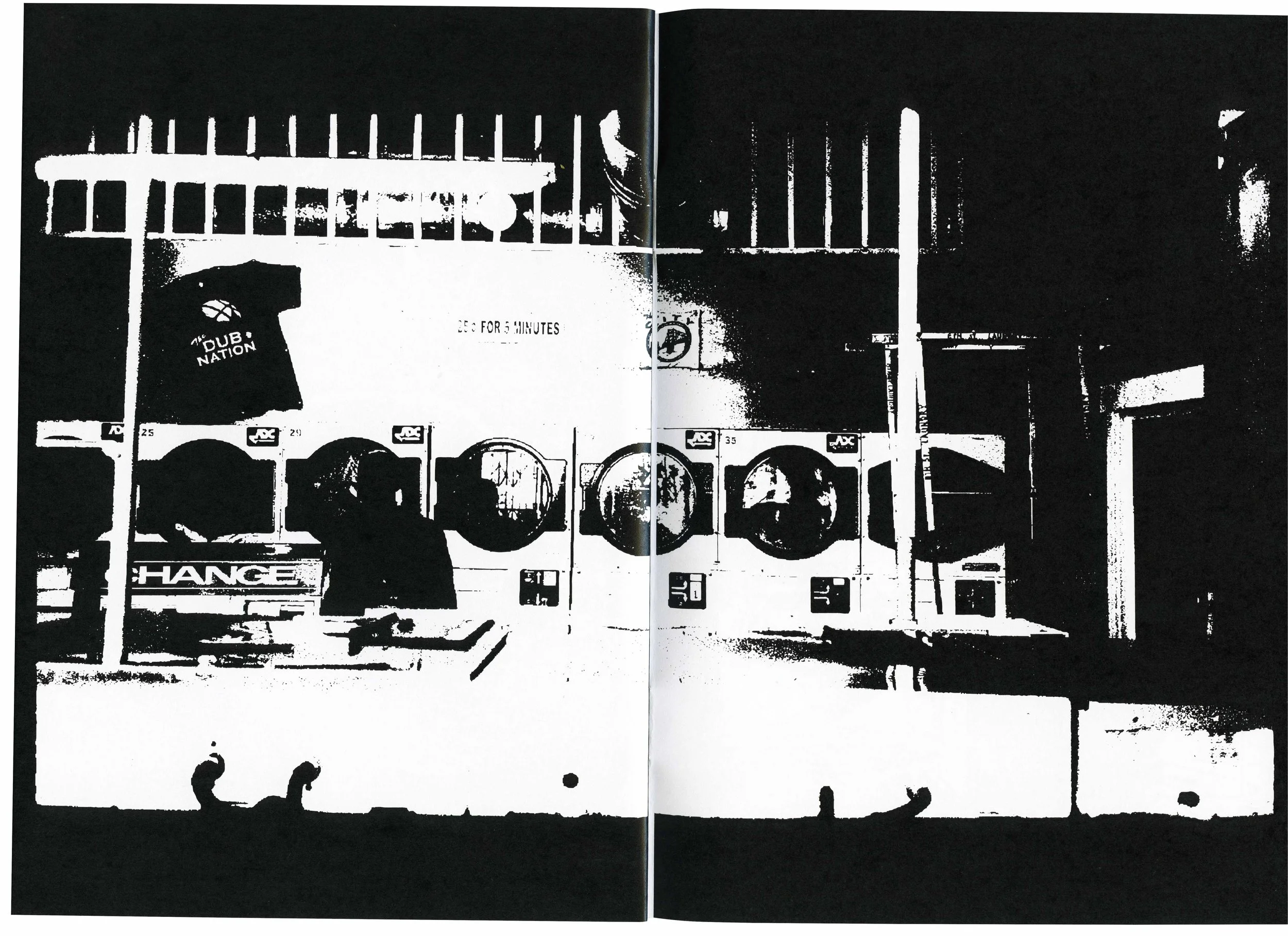 Black-and-white image of a train station platform with various signs and a train in the background. The image has a high contrast, almost silhouette-like appearance.