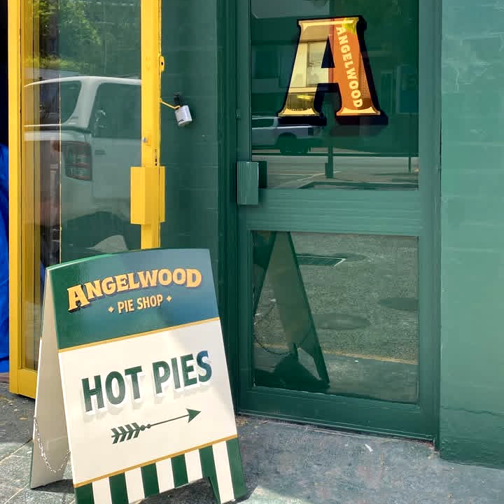 A sign outside Angelwood Pie Shop advertising hot pies with an arrow pointing to the right.