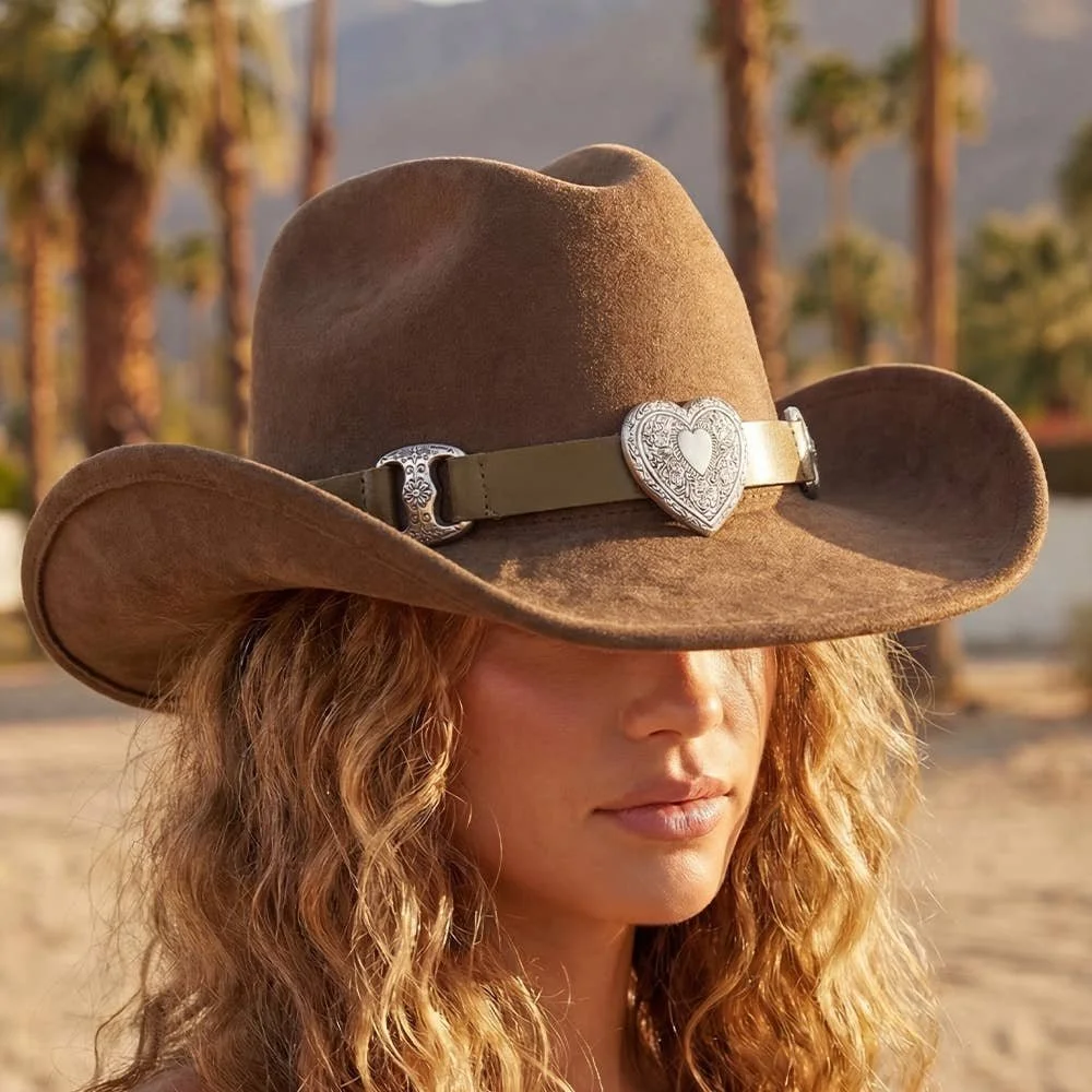Woman wearing a brown cowboy hat with a heart-shaped hatband buckle.