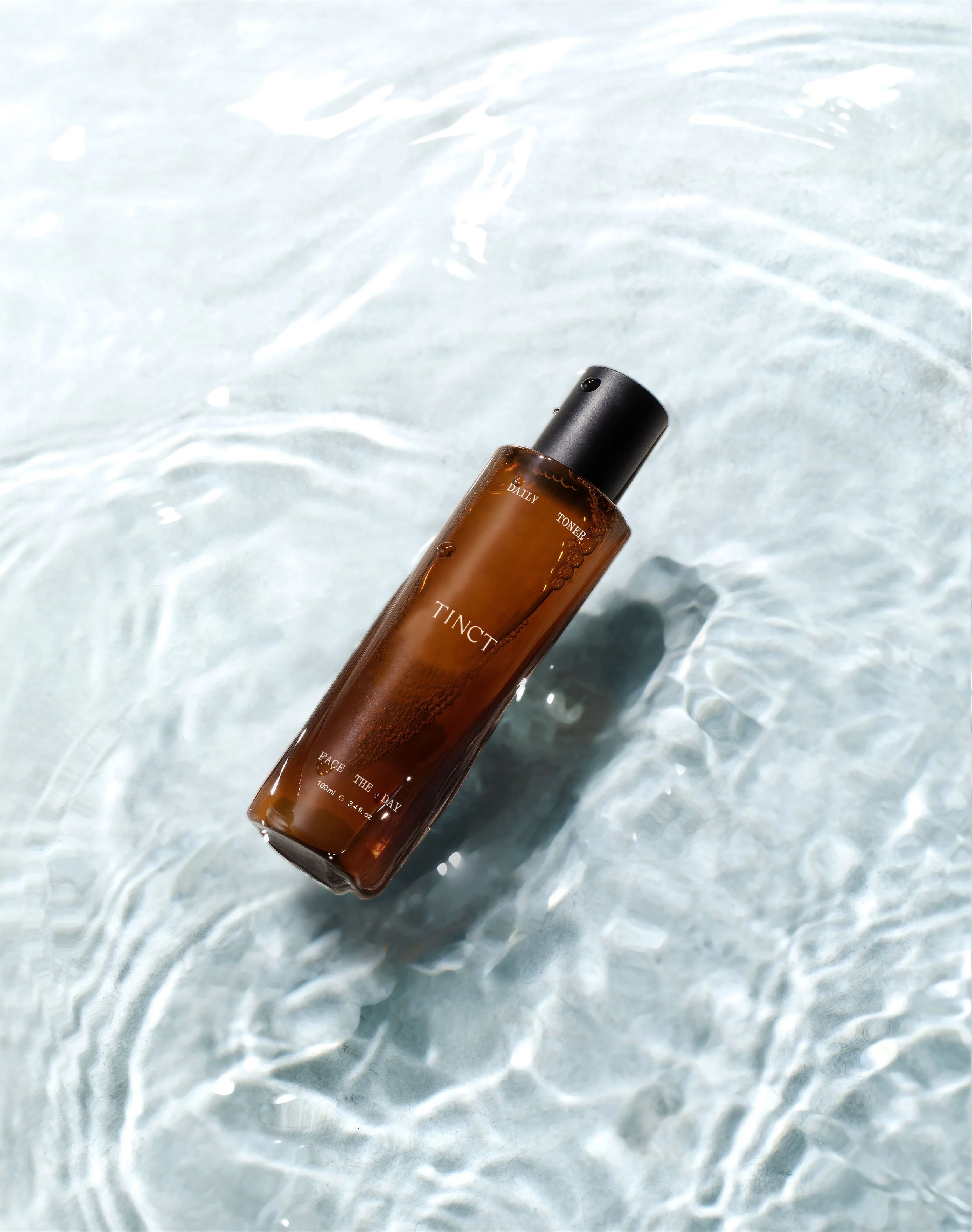 A brown bottle labeled 'TINCT F' floating in clear water with gentle ripples.