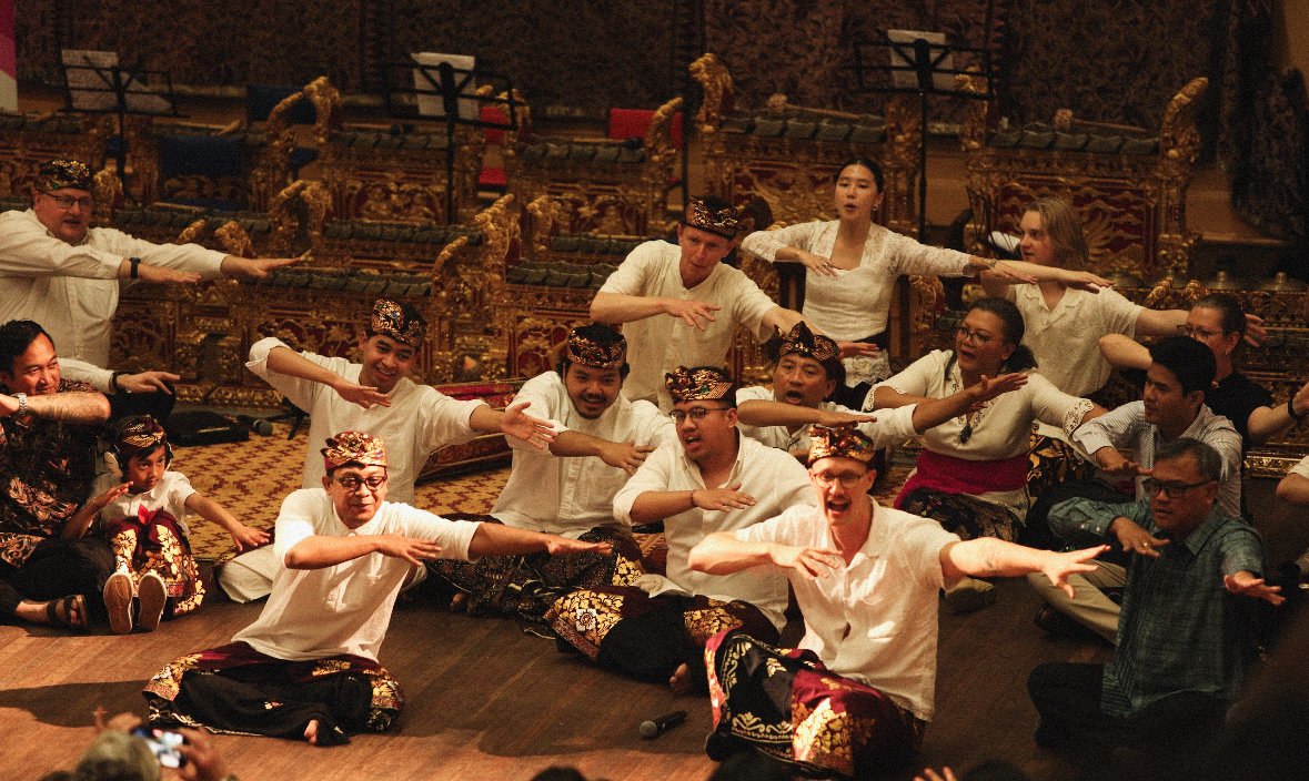 Group of people performing a traditional dance in a cultural setting, wearing traditional attire and hats.