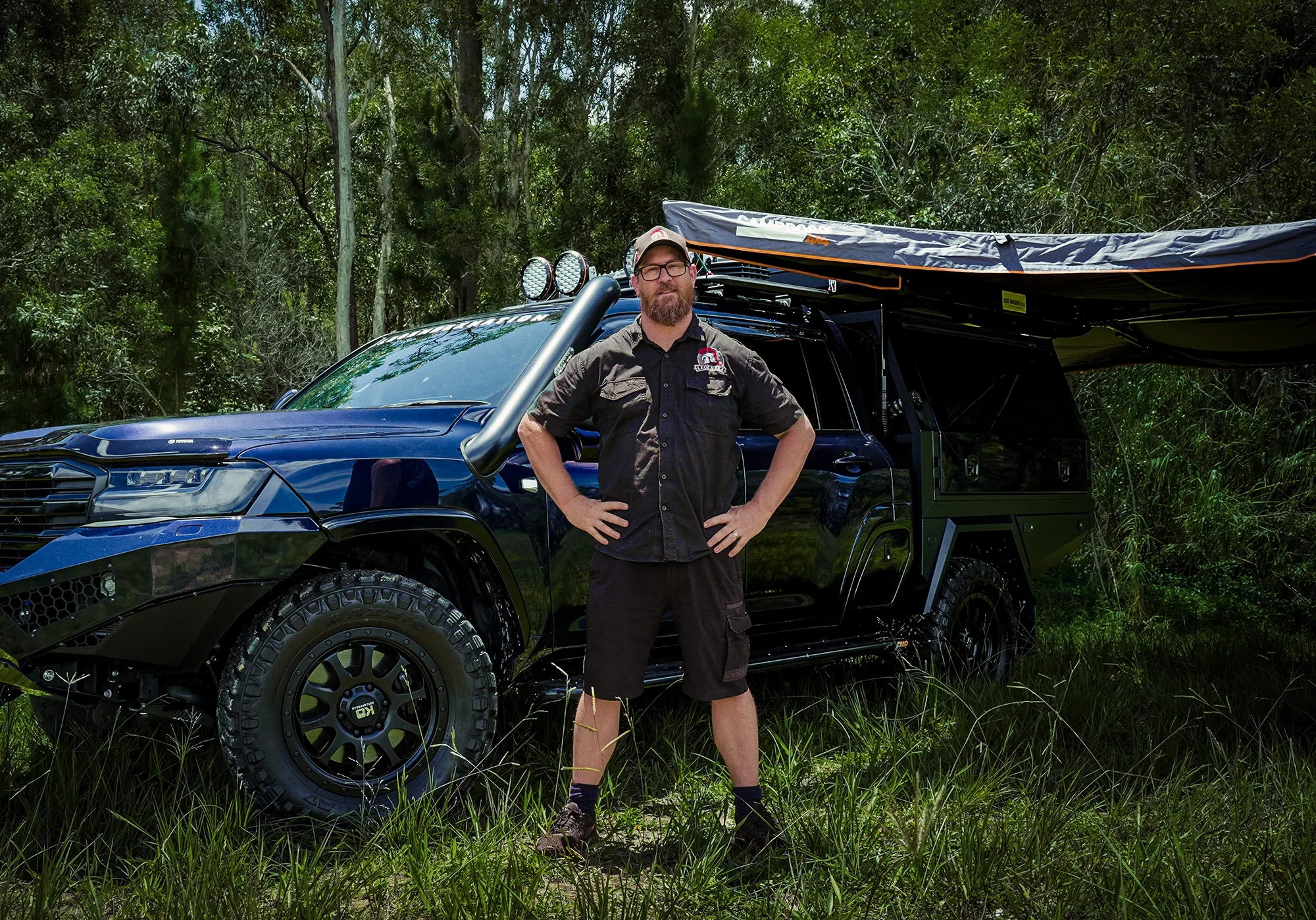 Portrait of a 4WD business owner standing outdoors beside a custom modified off-road vehicle, captured with a natural and rugged automotive branding style.