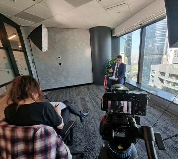 BTS photo showing a crew member and camera setup filming a businessman during a professional interview shoot