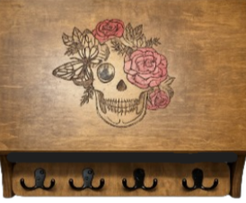 Decorative wooden table with a skull and flower design on the surface and five hooks underneath.