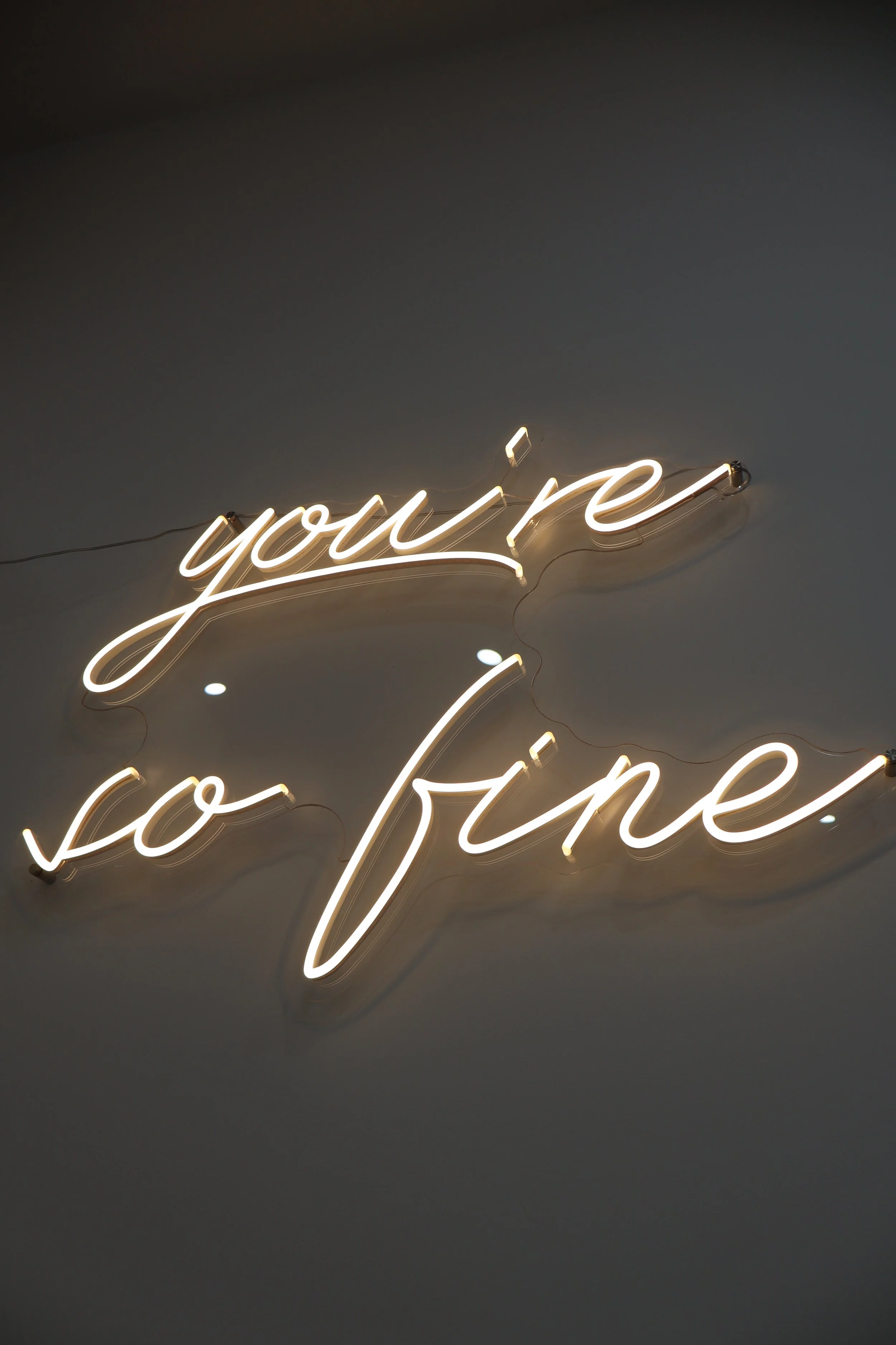 Neon sign that reads 'you're so fine' in cursive script, mounted on a wall.