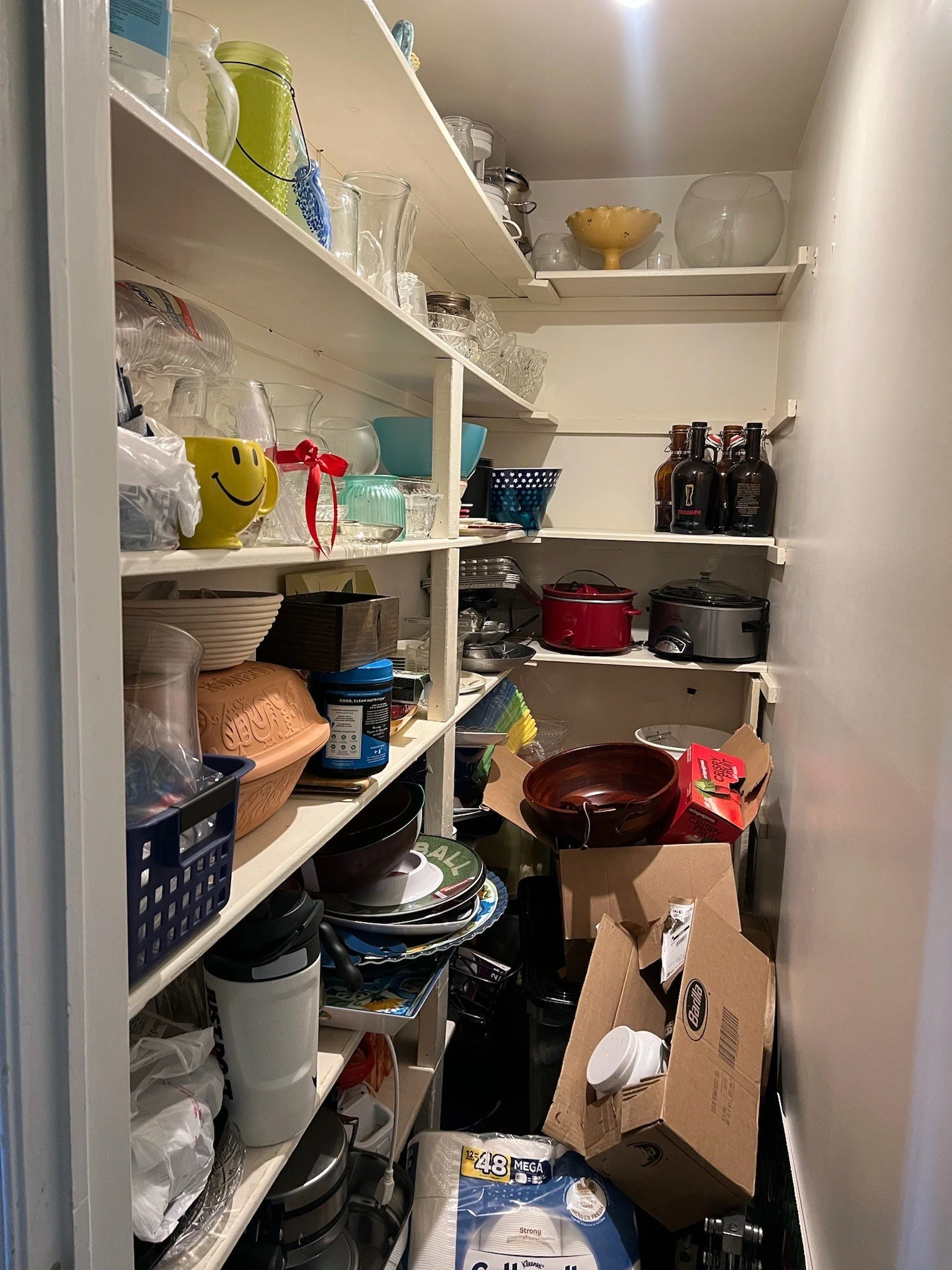 Pantry filled with shelves holding various glassware, kitchen appliances, cardboard boxes, and household items. Professionally organized by Uncluttered Spaces located in Bucks County. 
