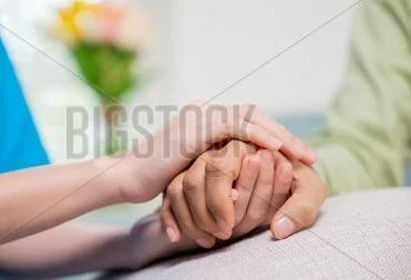 Two people holding hands in a gesture of comfort and support.