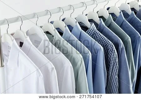 Row of assorted men's dress shirts hanging on hangers.