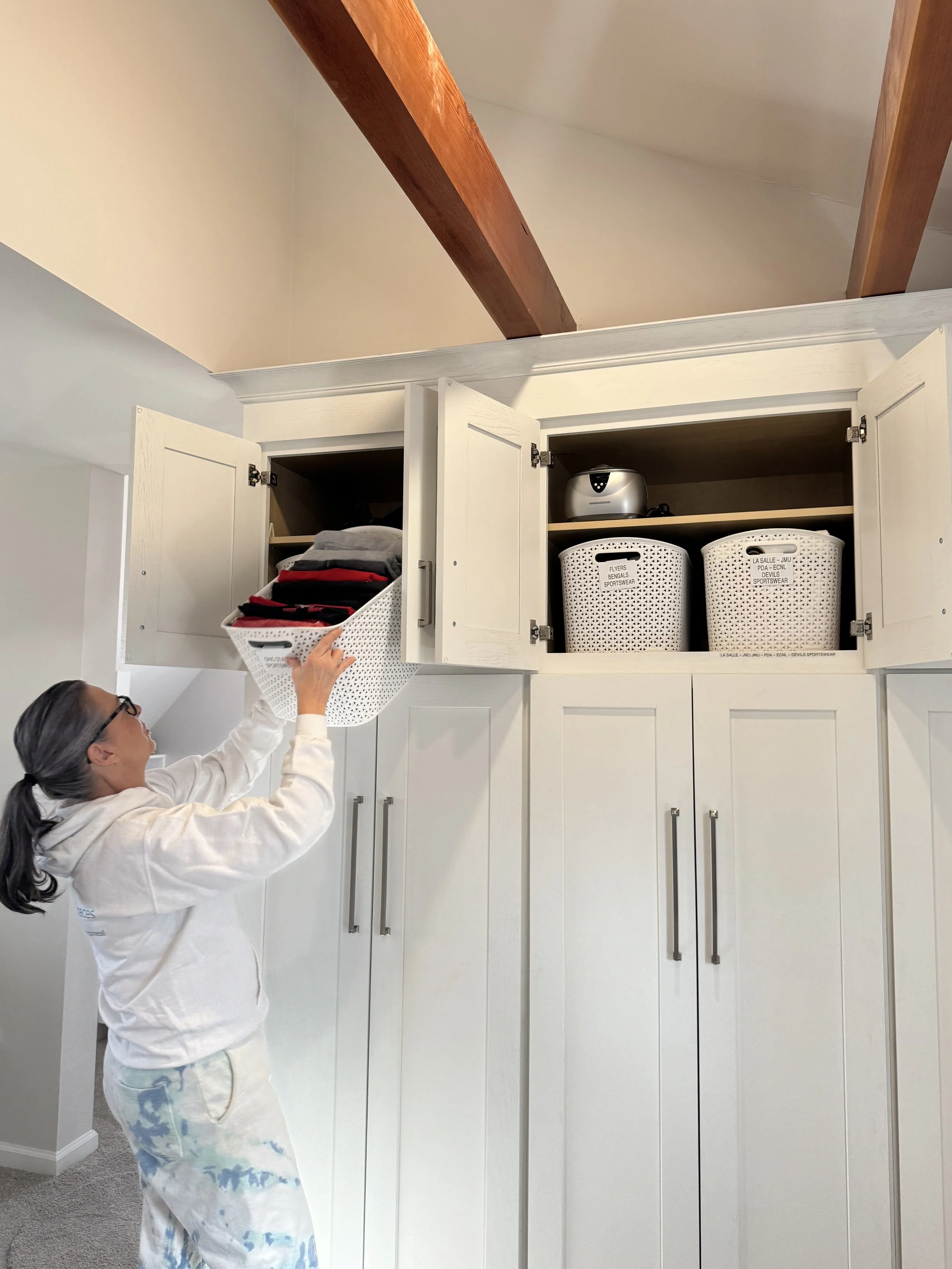 A woman pushes a storage basket into a cabinet