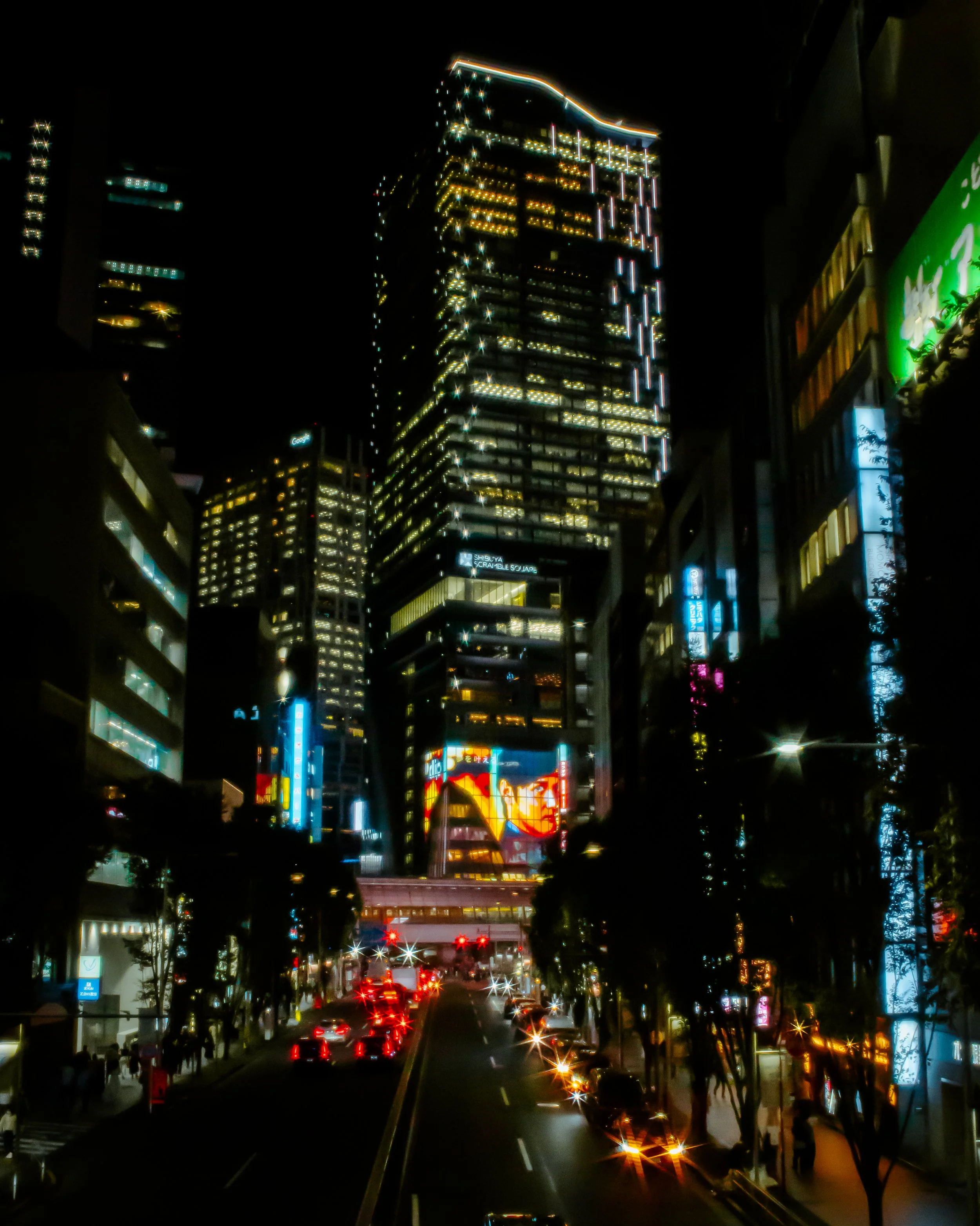 Nighttime cityscape with illuminated skyscrapers, traffic, and neon signs.