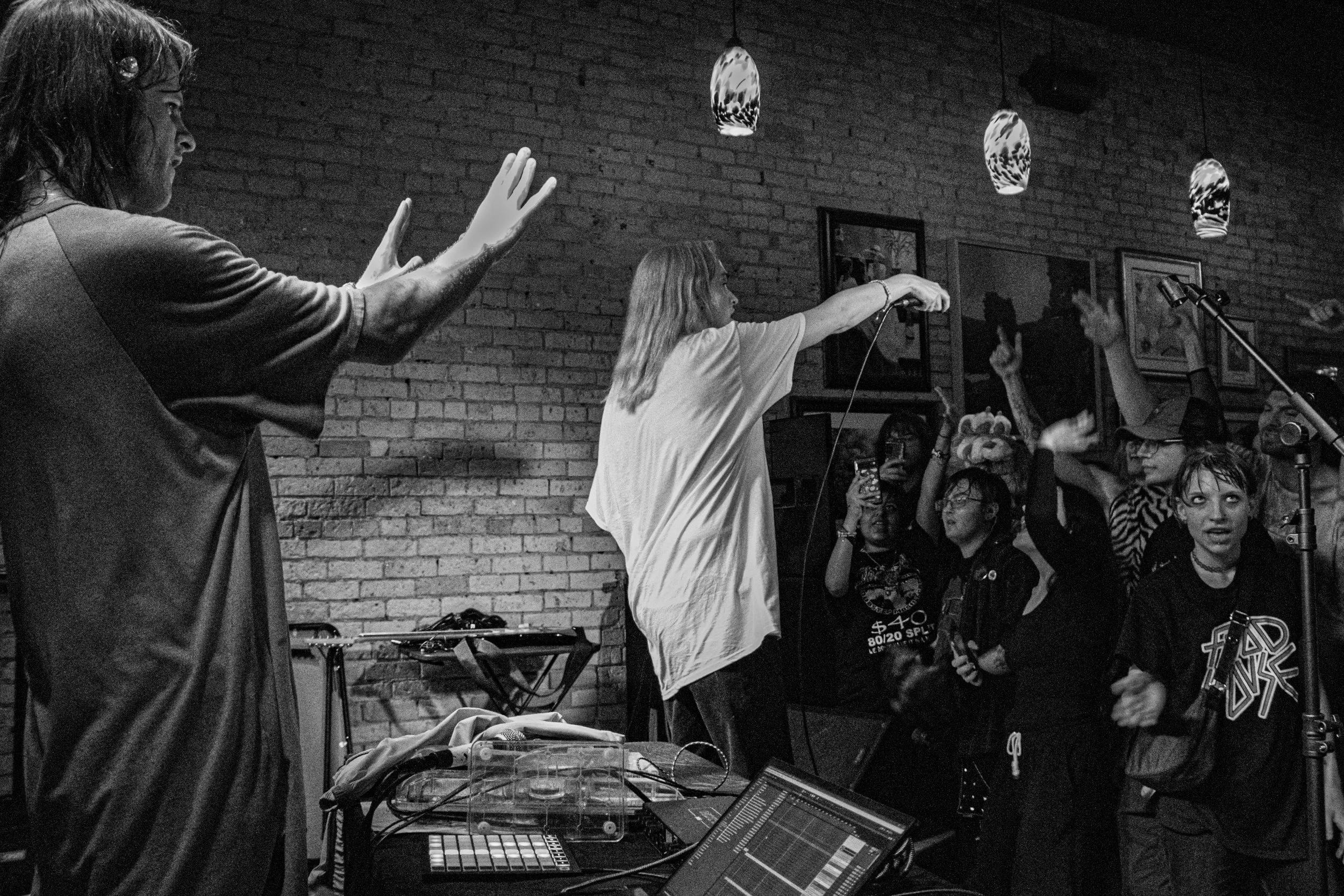 People enjoying a live music performance at an indoor venue with brick walls and ceiling lights.
