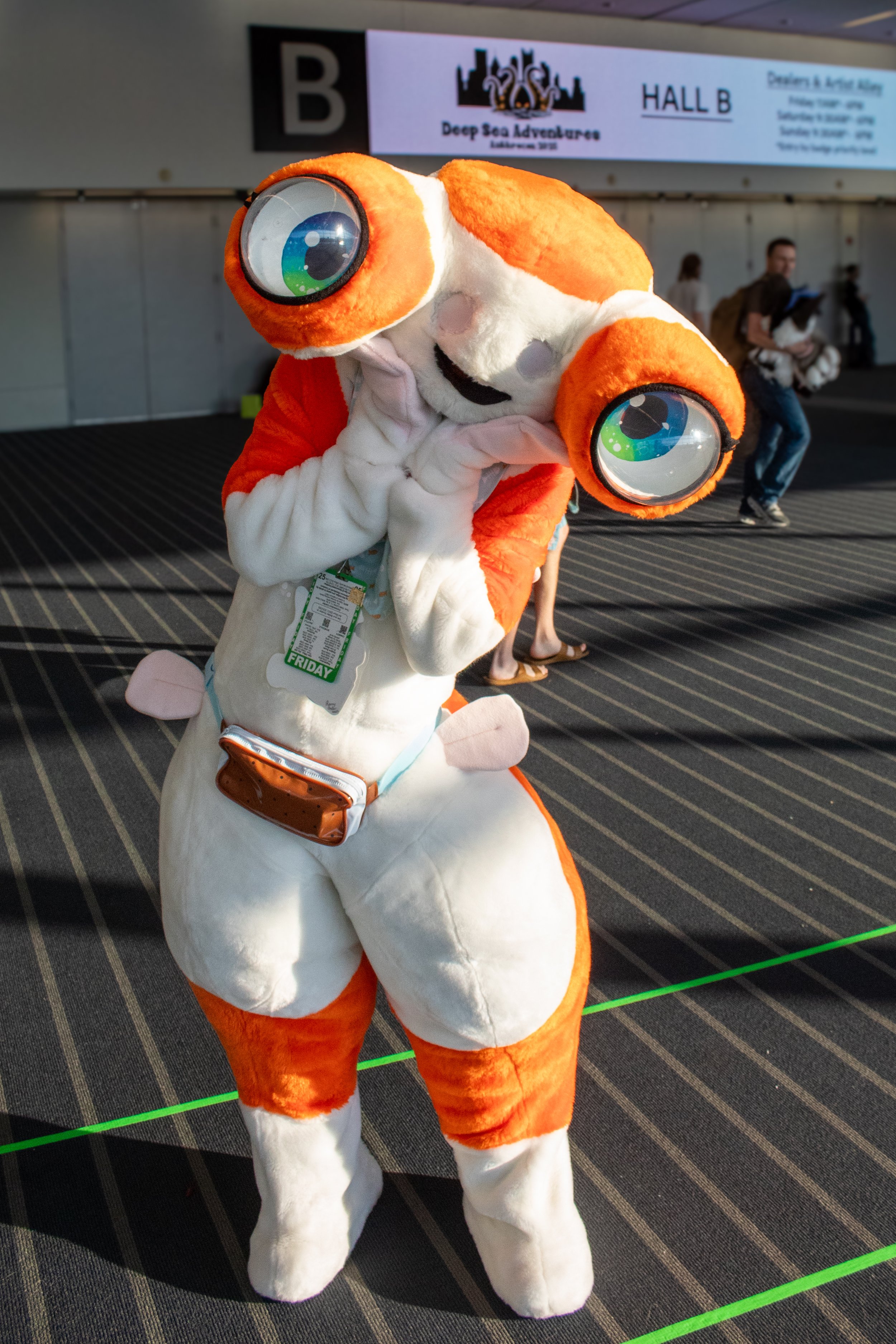 Person in a clownfish mascot costume at an indoor event, with a sign in the background that says 'Deep Sea Adventures' and 'Hall B'.