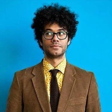 Richard Ayoade, author of "Afterthoughts" and director of "Submarine", on stage for 92 Speakers delivering keynotes on "The Wisdom of the Unreflective" and 2026 social friction.