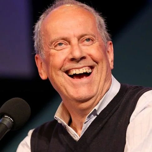 Gyles Brandreth, author of "Prose and Cons" and host of the Rosebud podcast, on stage for 92 Speakers delivering keynotes on "The Seven Secrets of Happiness" and the 2026 linguistic evolution.