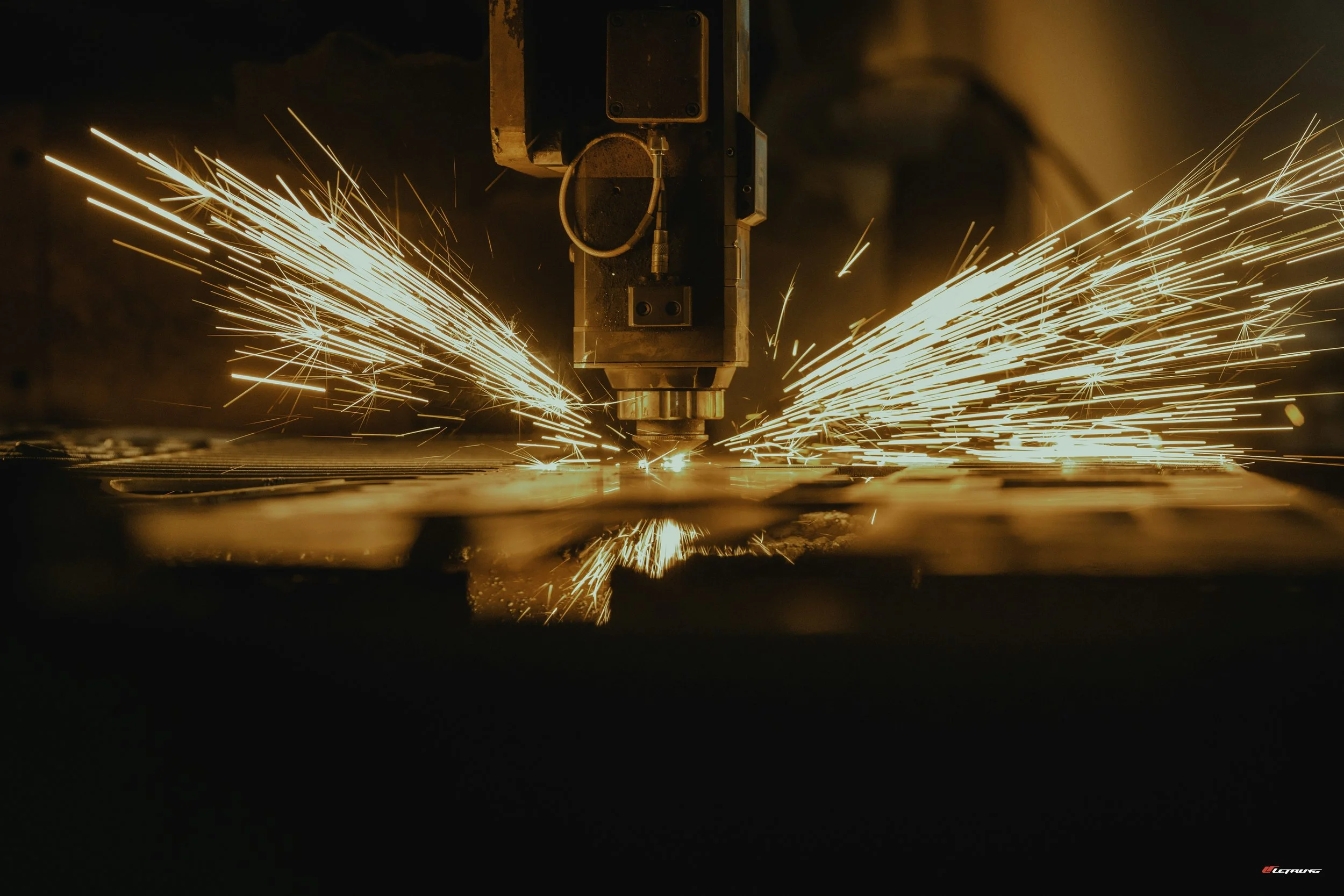 A robotic welding machine producing bright sparks as it welds metal.