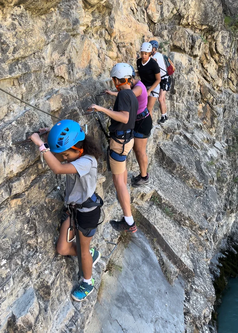 A familly being helped by a climbing instructor to progress in a via ferrata close to Granada