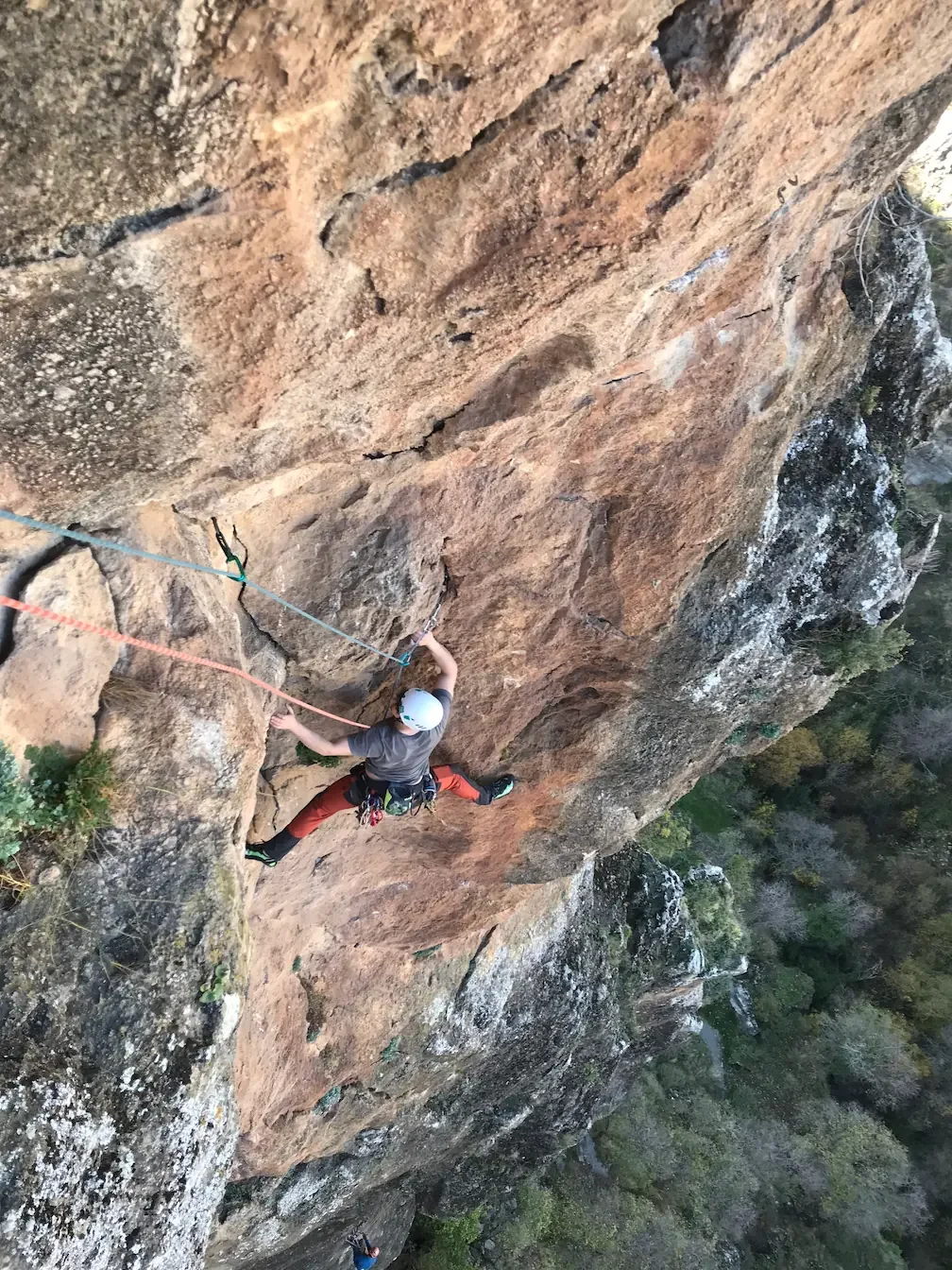 A guy is finishing the last pitch of a trad route during a guided trad climbing with a certified climbing guide
