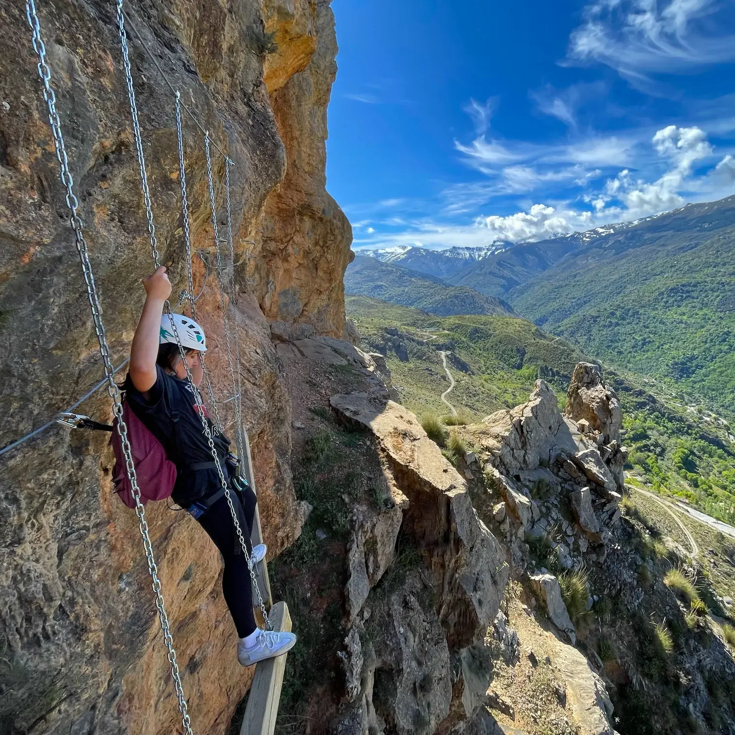 A girl facing Sierra Nevada during the via ferrata "La Araña"