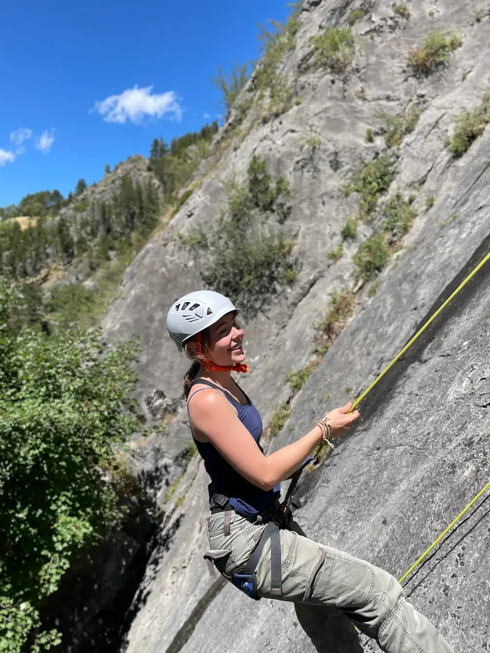 A gril smilling and going down from her first tope rope rock climbing during a beginner course 