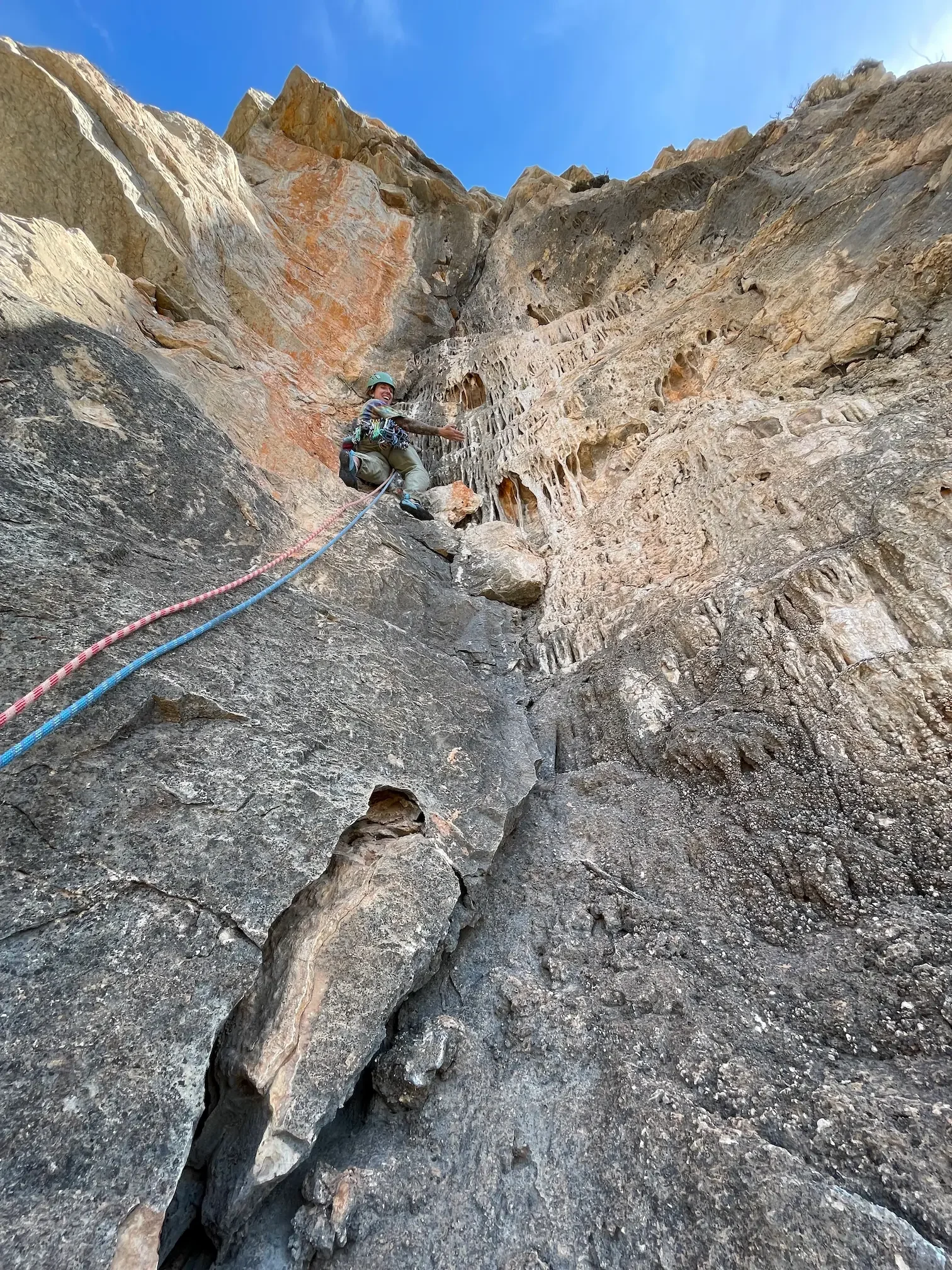Trad climber ascending limestone wall on multi pitch route in Granada