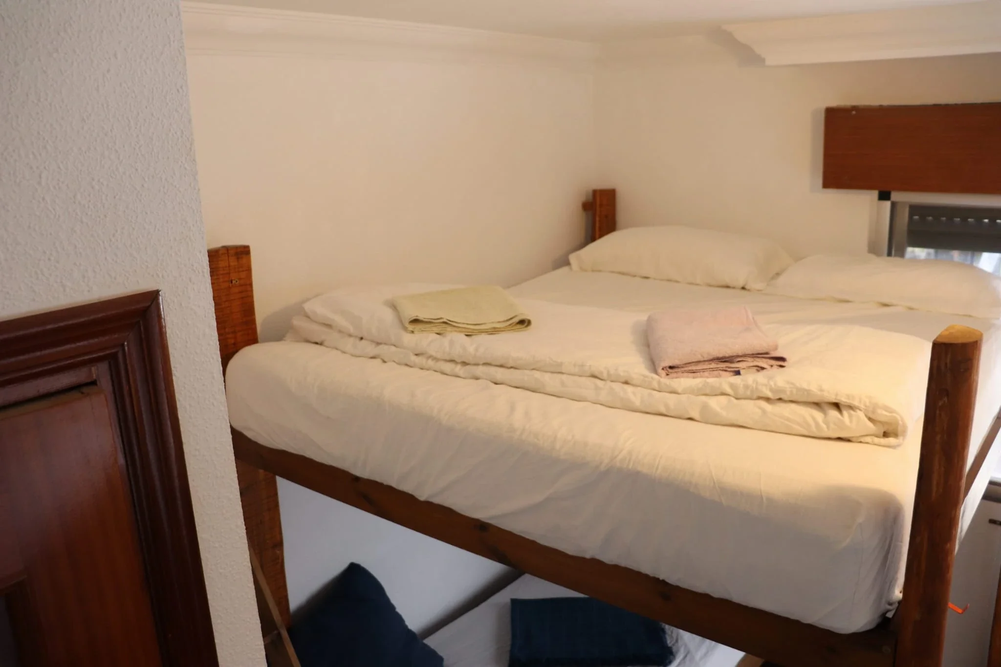 Guest room with a bunk bed, topped with white bedding and pillows, in a cozy hostel