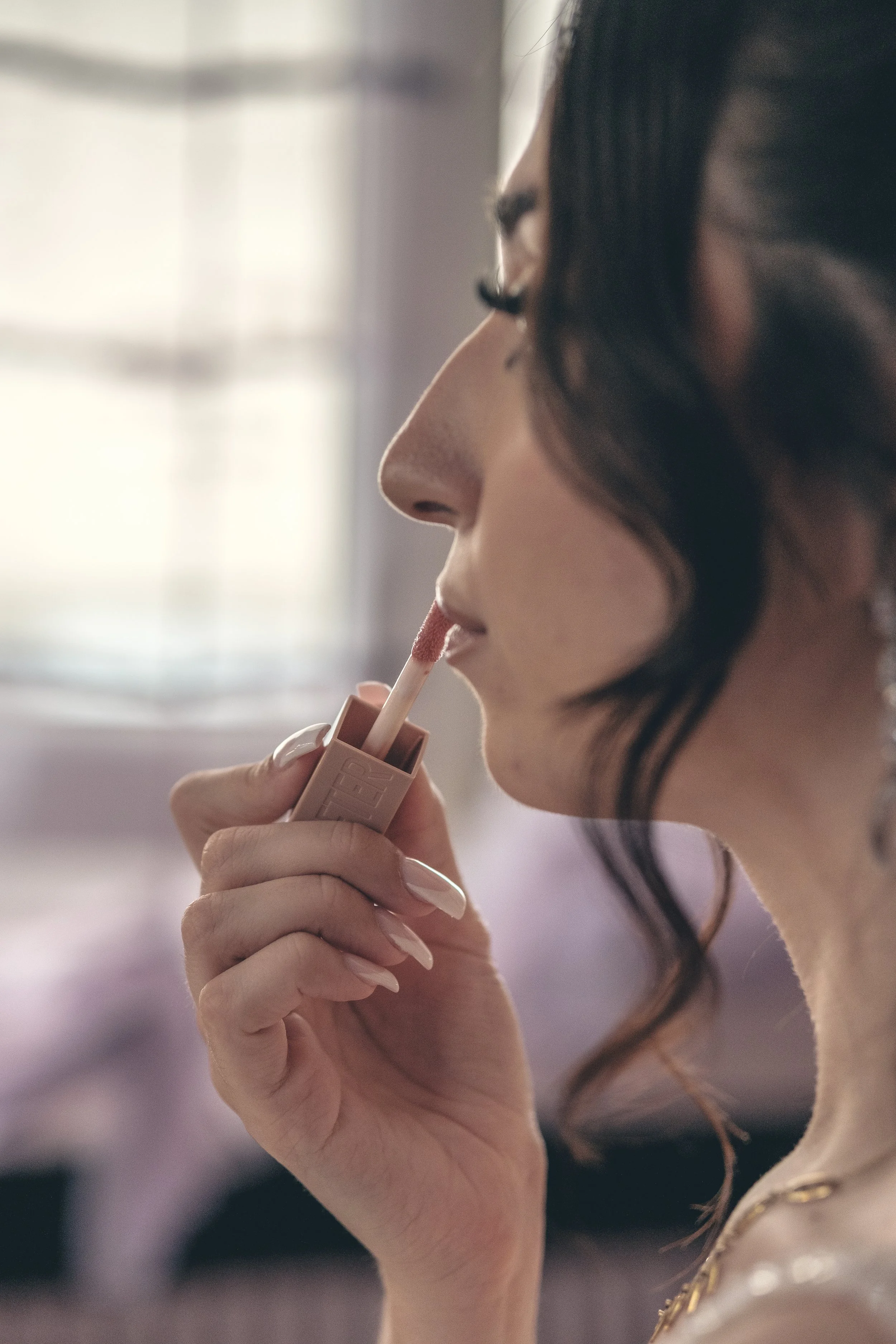Une femme en train d'appliquer du gloss sur ses lèvres