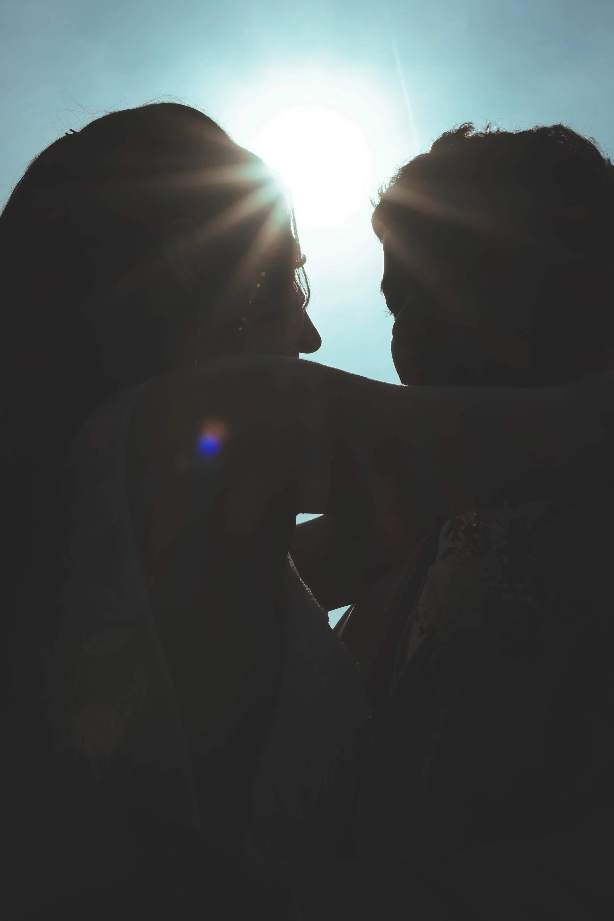 Silhouettes de deux personnes proches, face à face, avec le soleil en arrière-plan.