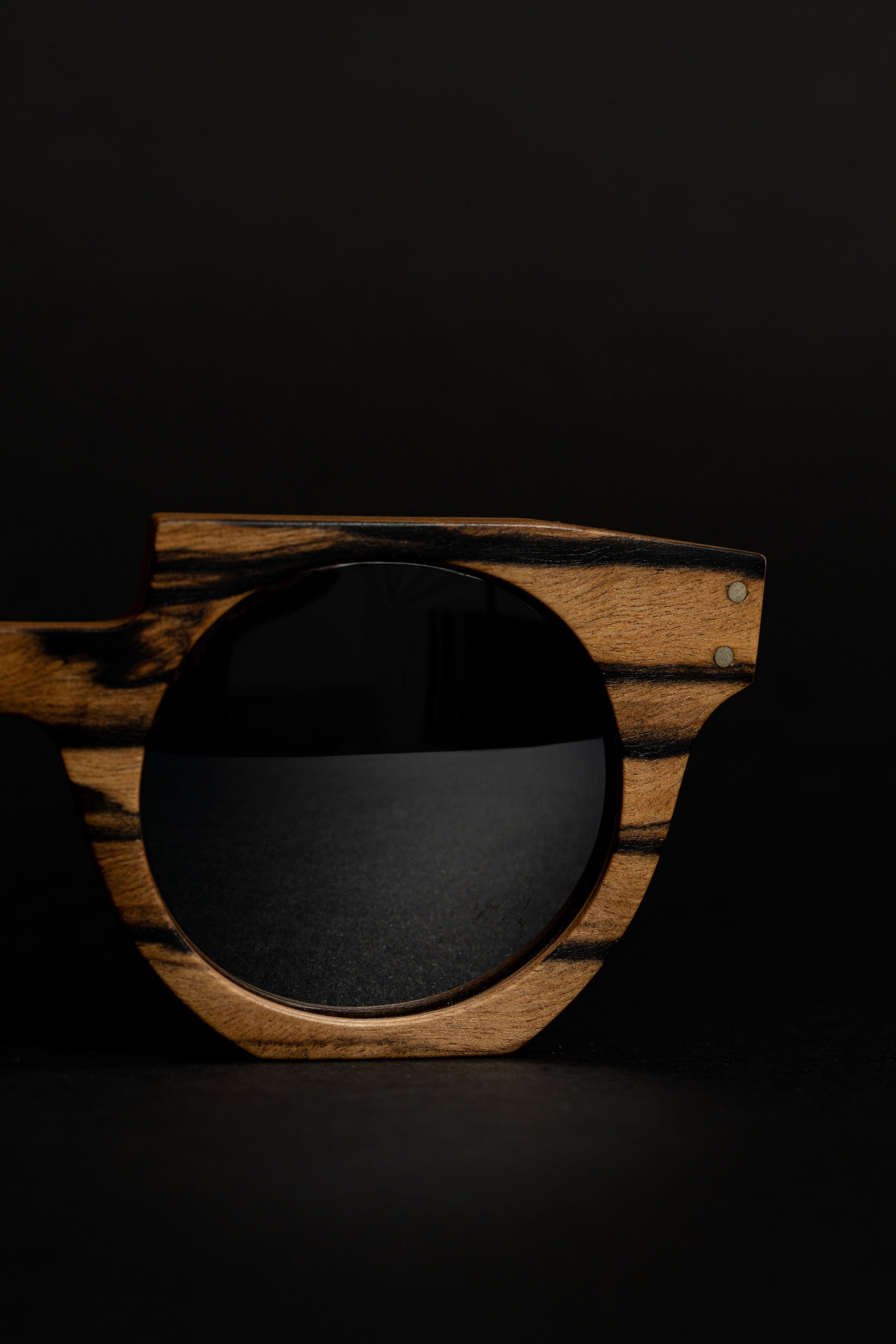 Une monture de lunettes en bois avec un design en tranches naturelles, posée sur un fond noir.
