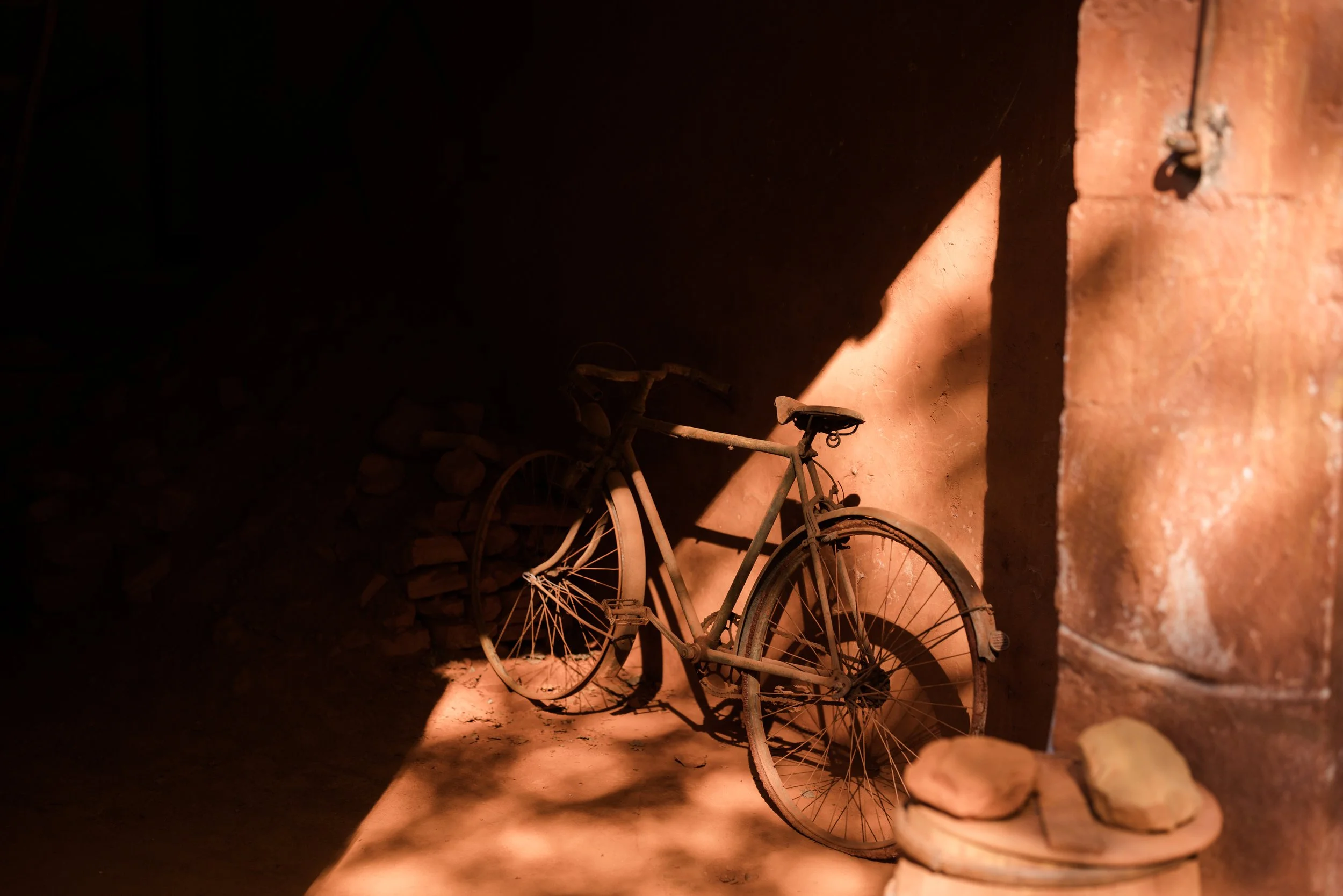 Vélo ancien abandonné dans une pièce obscure avec lumière tombant sur lui.